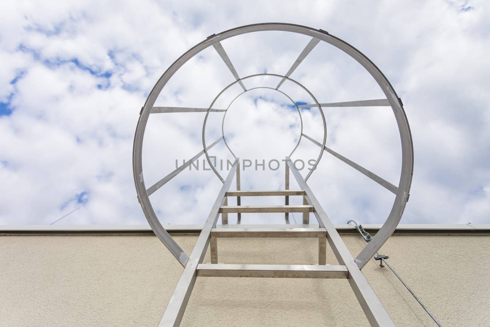 Bottom view of the stainless steel ladder mounted on the building facade. Technical access on the outside of the building to the higher part of the roof.