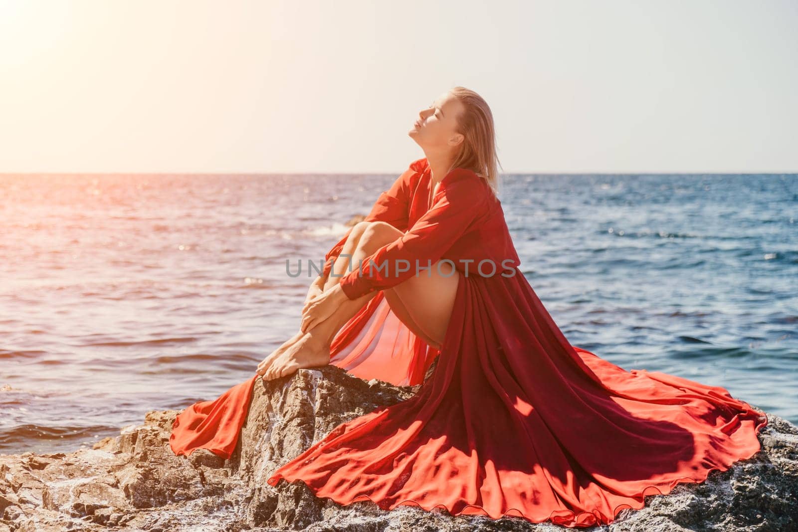 Woman travel sea. Happy tourist in long red dress enjoy taking picture outdoors for memories. Woman traveler posing on beach at sea surrounded by volcanic mountains, sharing travel adventure journey by panophotograph