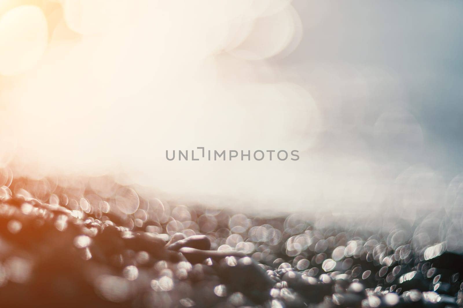 Blurred golden sea at sunset. The sun reflects and sparkles on the waves with bokeh, illuminating the golden sea. Holiday recreation concept. Abstract nautical summer ocean sunset nature background. by panophotograph