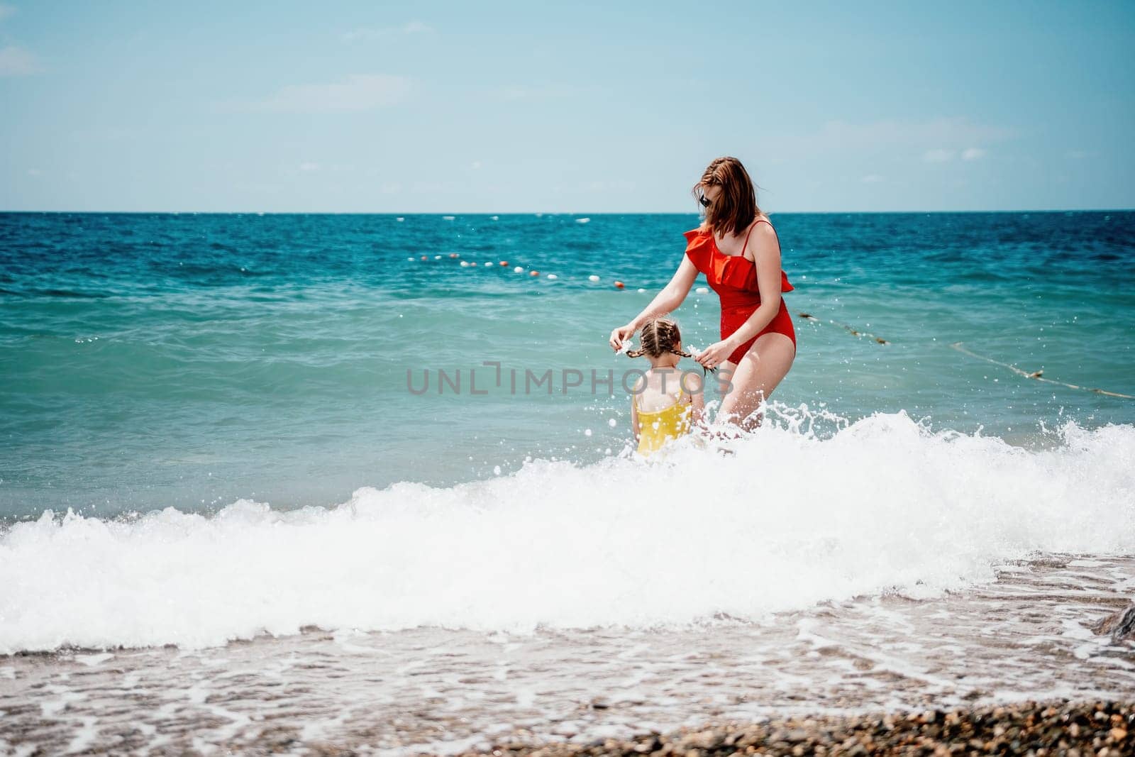 Happy loving family mother and daughter having fun together on the beach. Mum playing with her kid in holiday vacation next to the ocean - Family lifestyle and love concept.