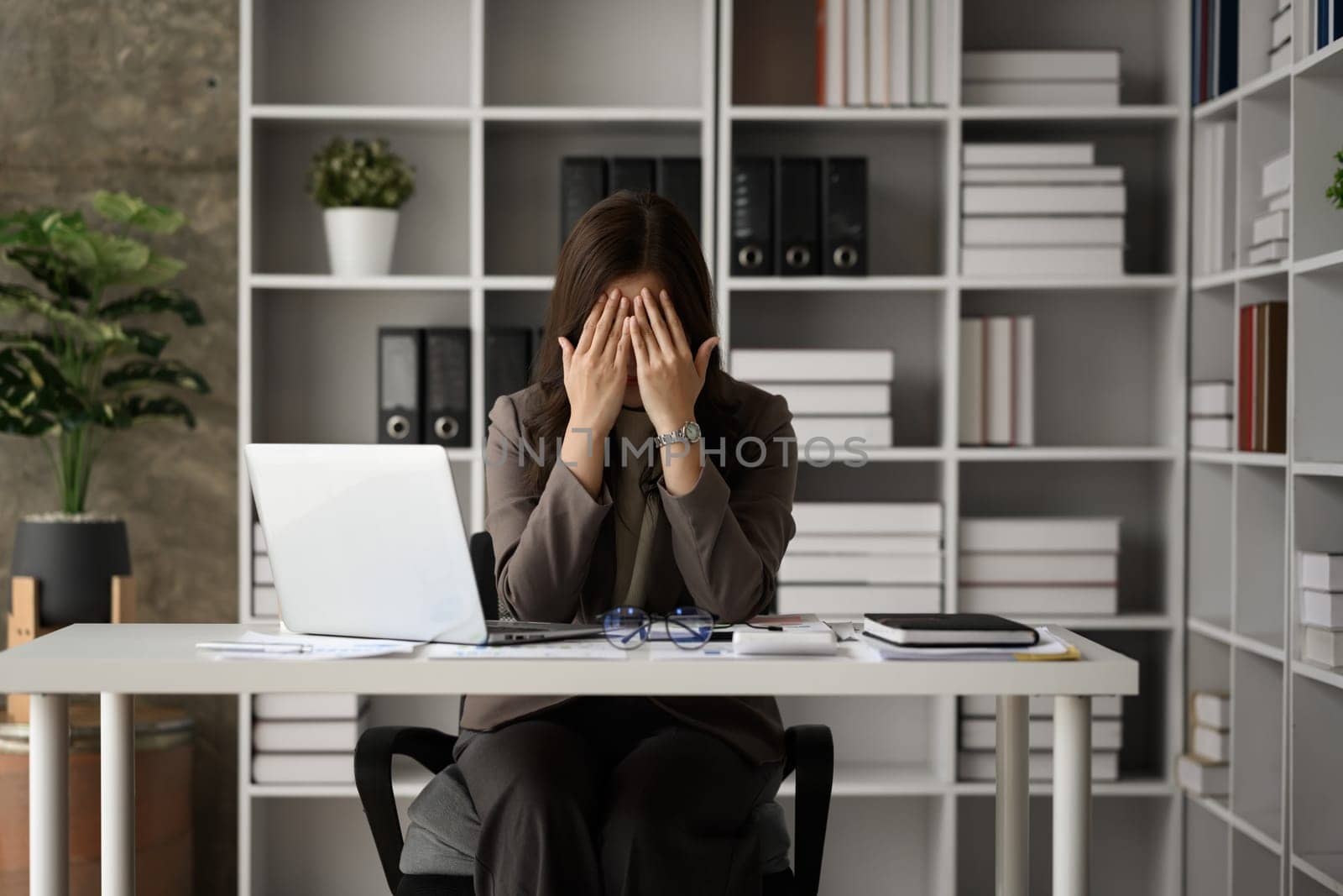 Upset female accountant covering face in front of laptop frustrated by bad news, tired of computer work.