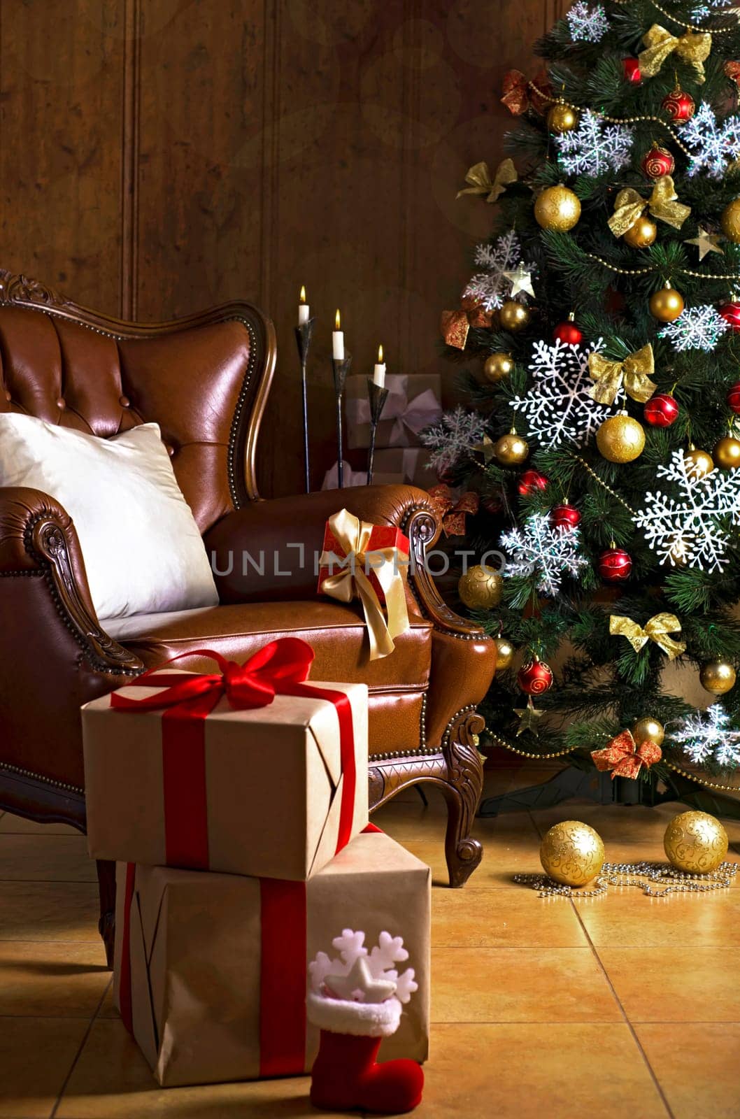 The living room in the house is decorated for Christmas. Christmas tree decorated for the holiday and a lot of gifts next to it. Cozy leather armchair next to the Christmas tree. Retro armchair in the house. by aprilphoto