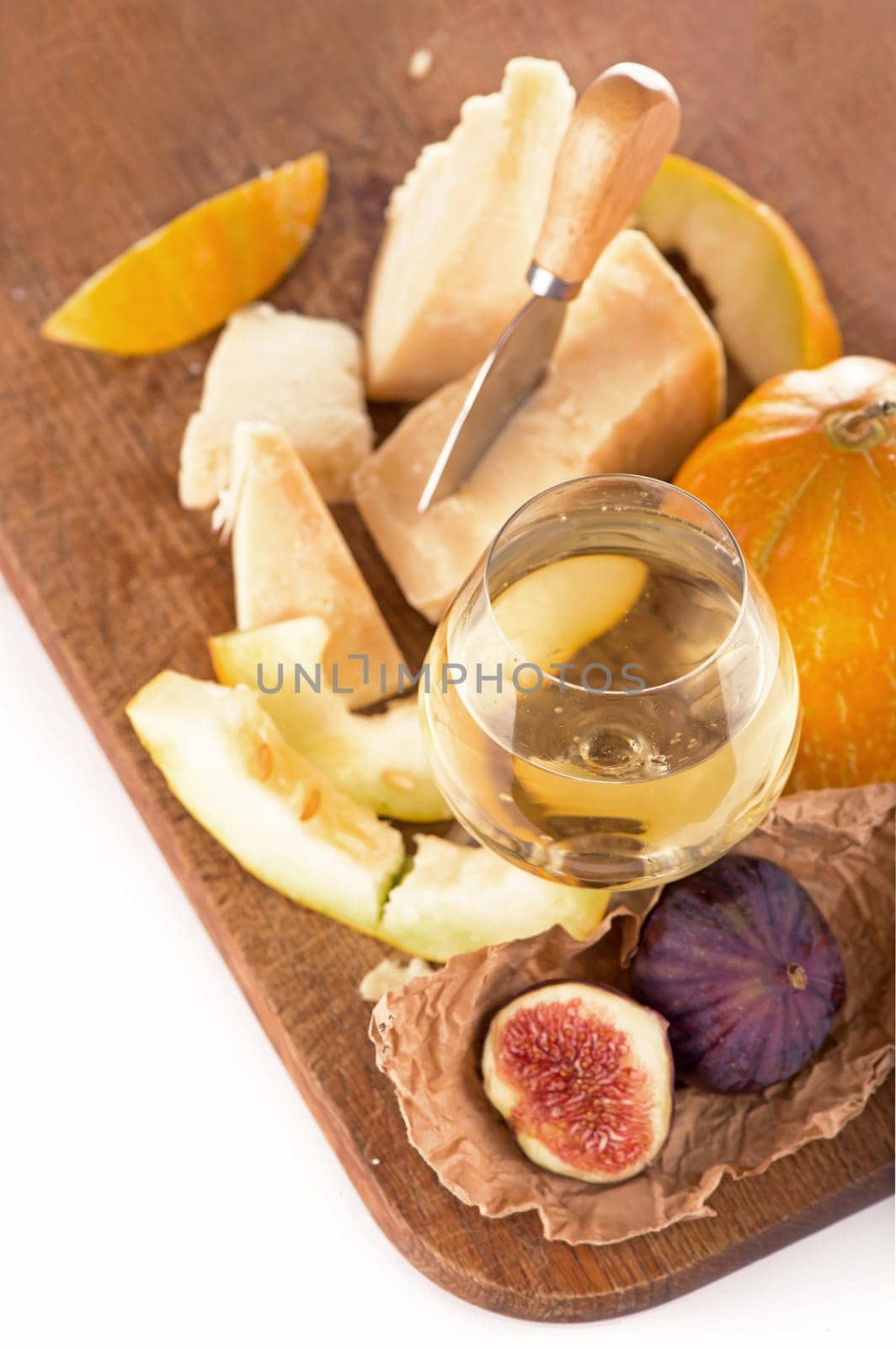 Cheese plate served with grapes, melon, figs, crackers, honey, nuts and white wine on a wooden table by aprilphoto