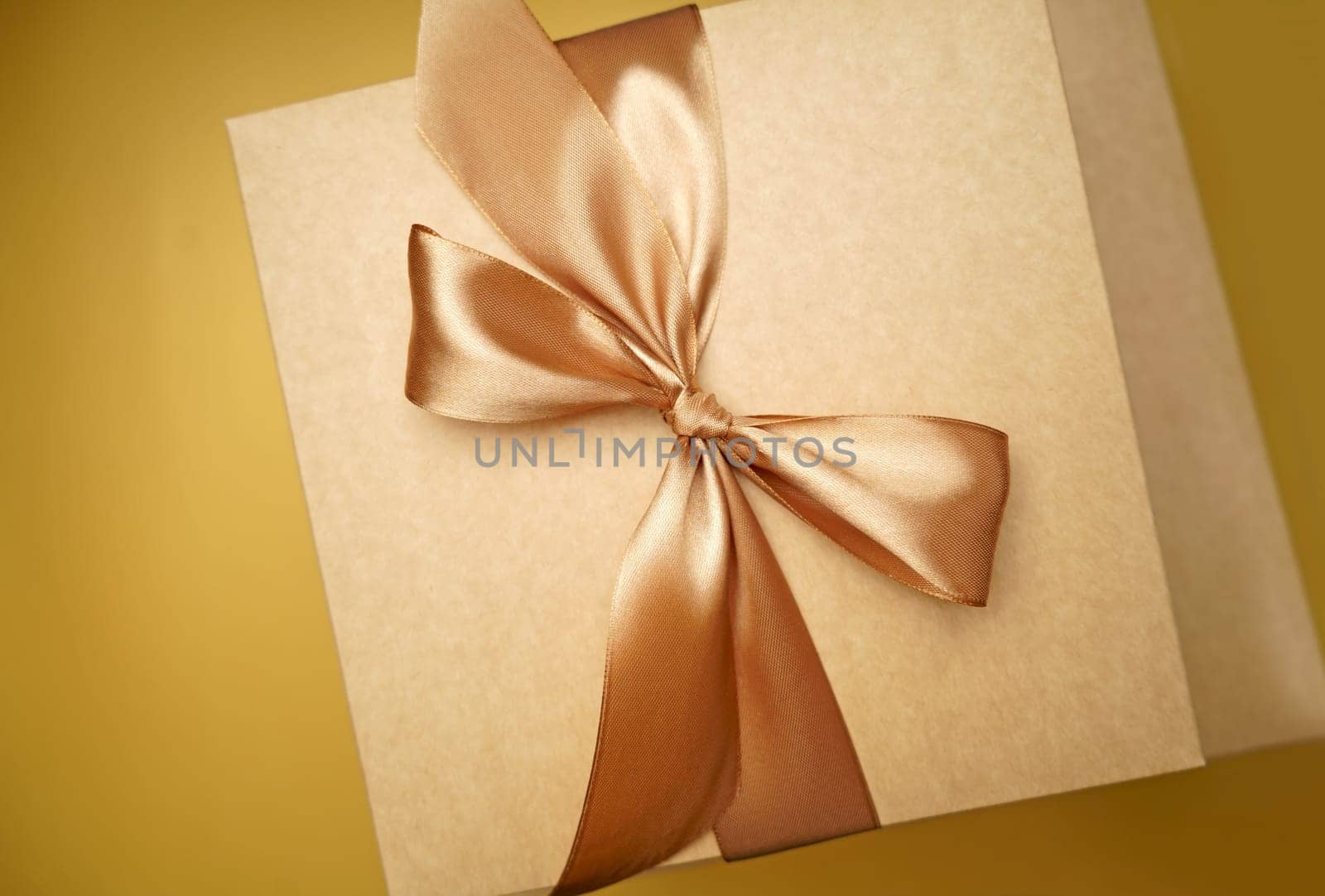 Square gift box. craft paper, yellow color bow knot, ribbons. paper background. sticker for text. Happy New Year package. top view