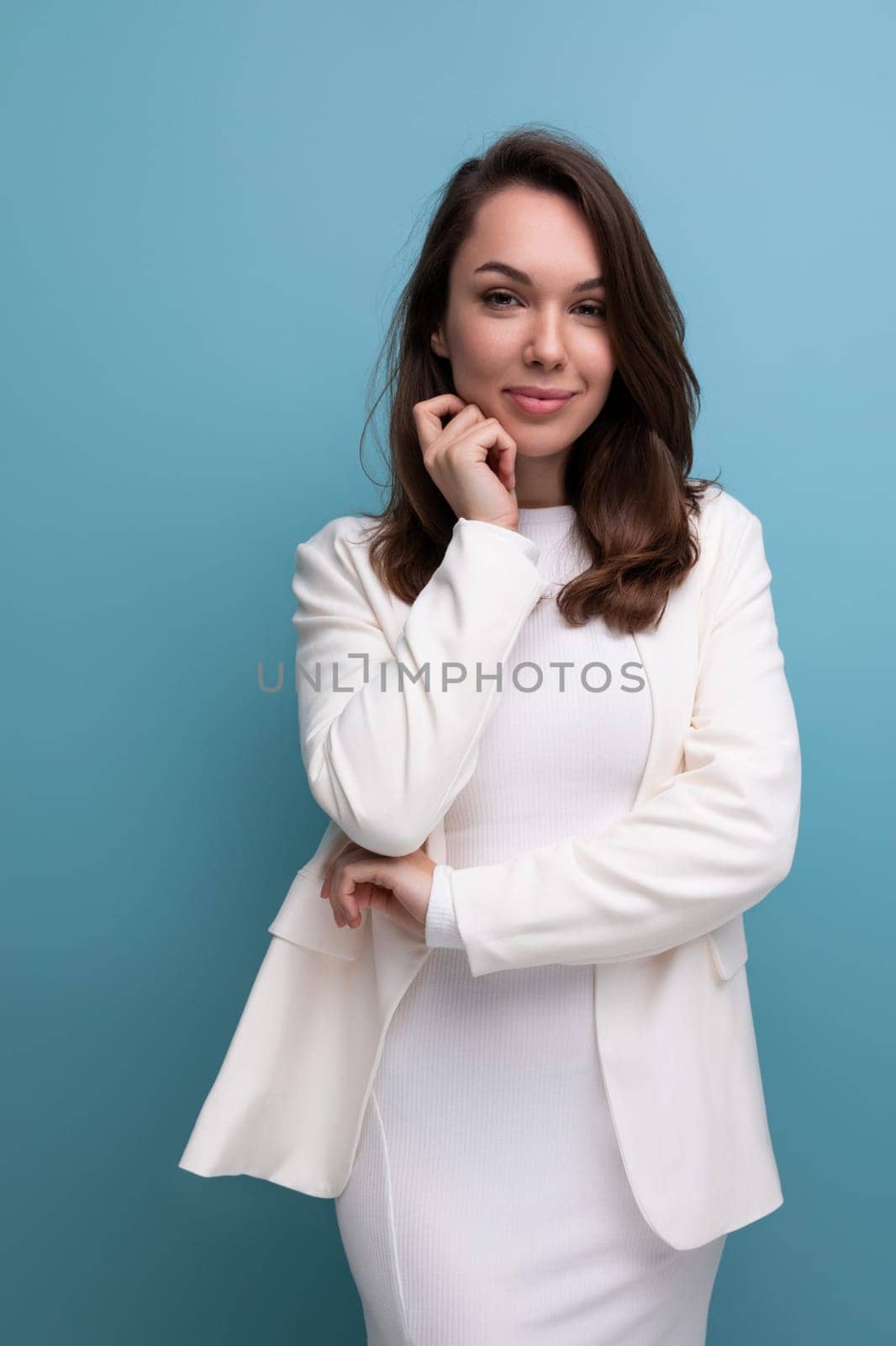 charismatic brunette young woman in white dress flirting on studio background.