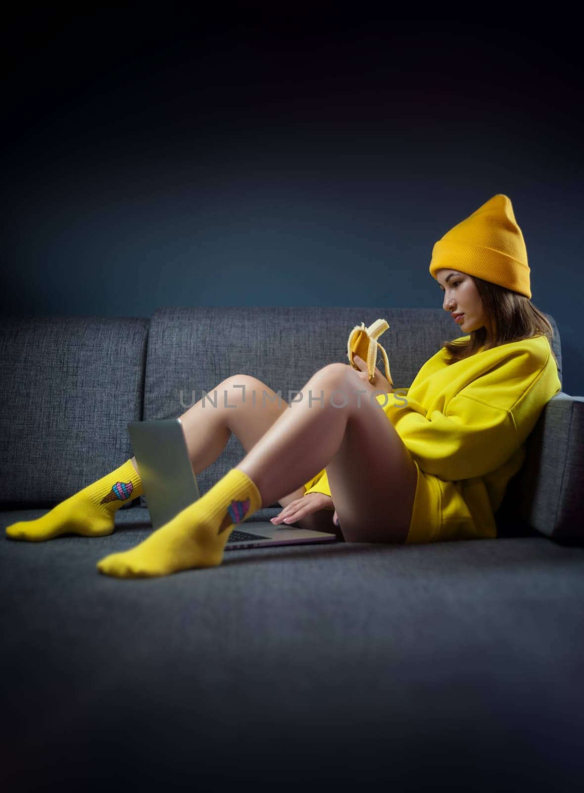 sexy girl in yellow clothes and a hat with a banana and a laptop on a dark background copy paste by Rotozey