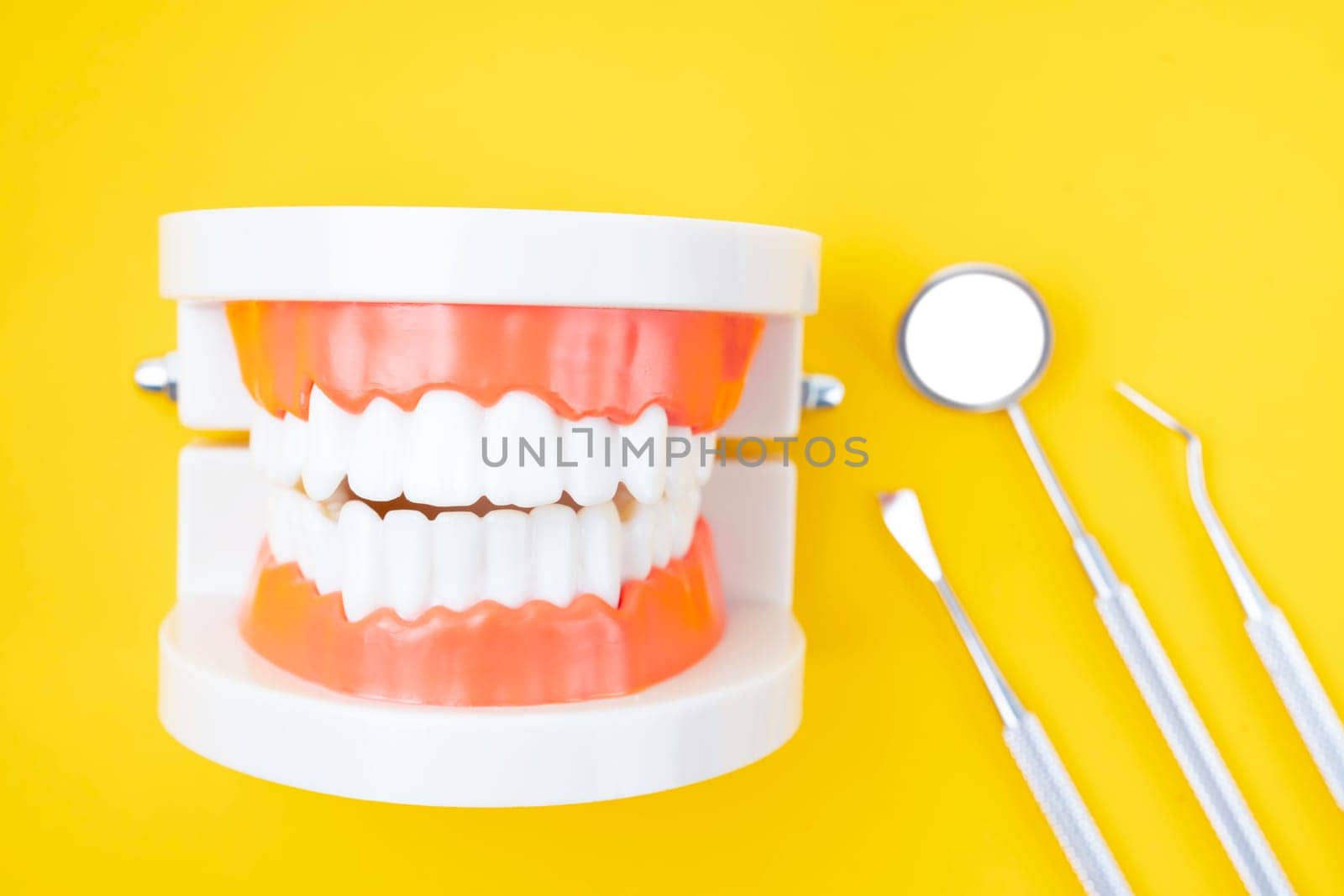 Dentures model and instrument dental on yellow background.