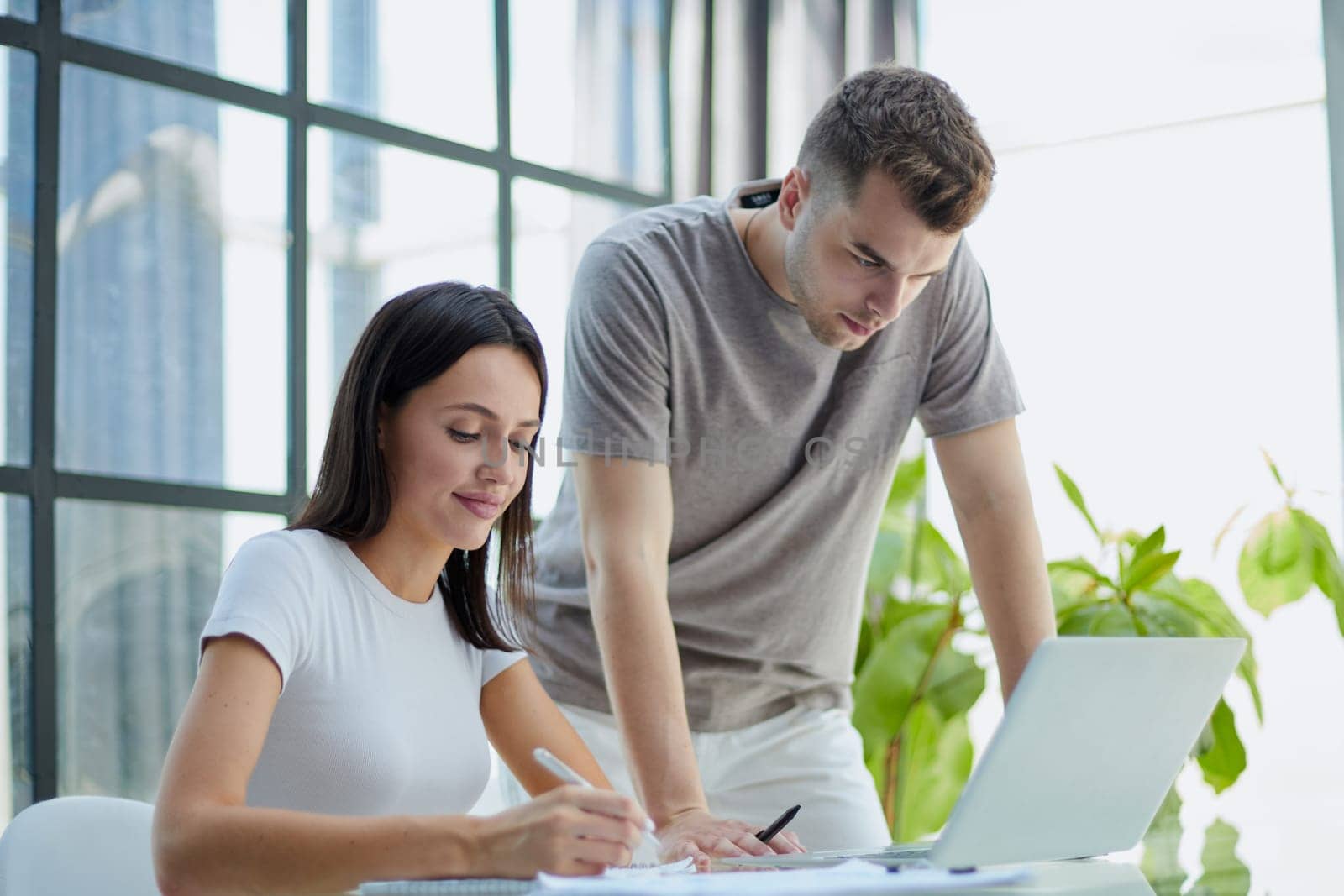 male ceo executive manager mentor giving consultation on financial operations to female colleague intern using laptop sitting in modern office