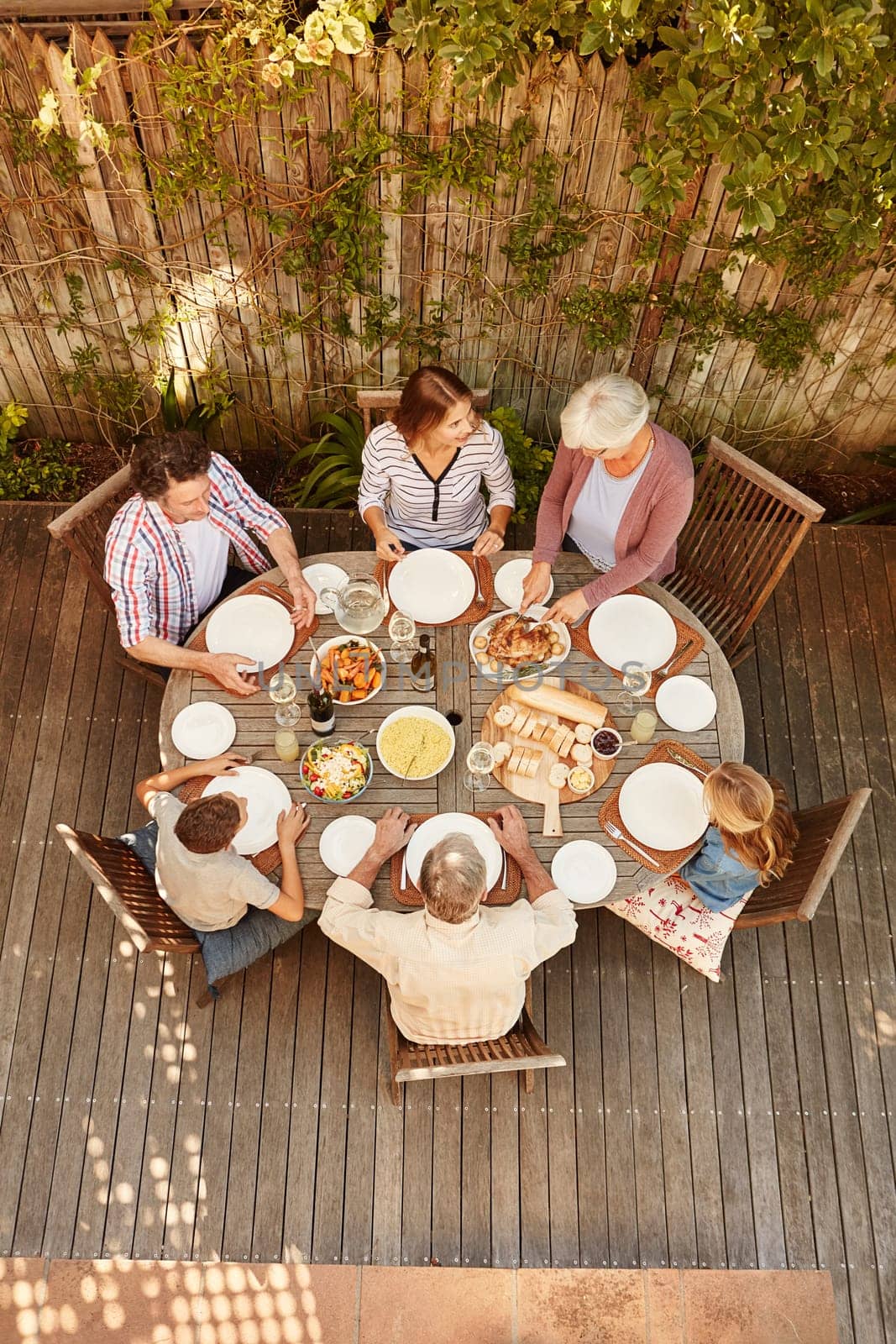 Family gatherings help them reconnect as a family. High angle shot of a family eating lunch outdoors. by YuriArcurs