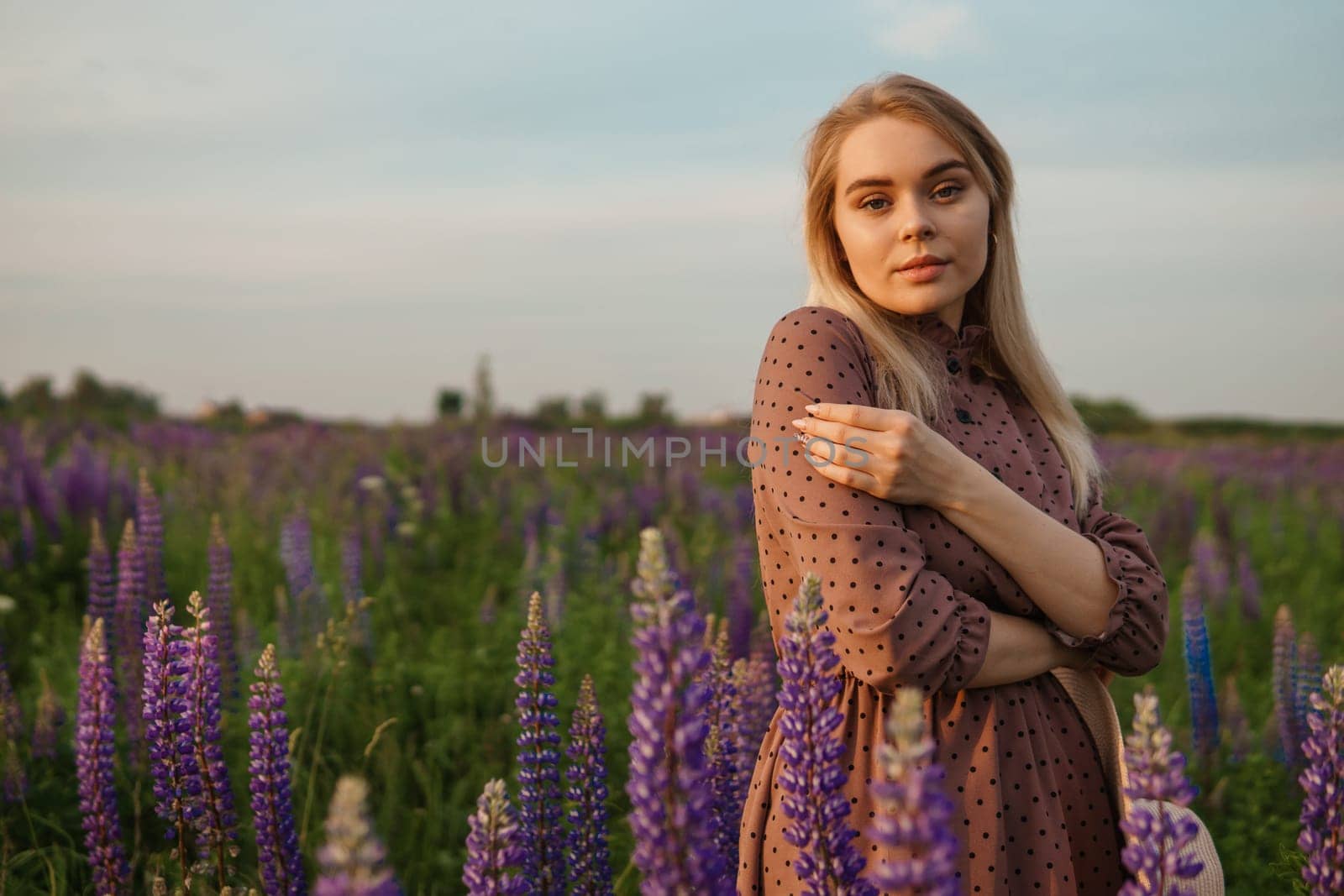 A beautiful woman in a straw hat walks in a field with purple flowers. A walk in nature in the lupin field by Annu1tochka