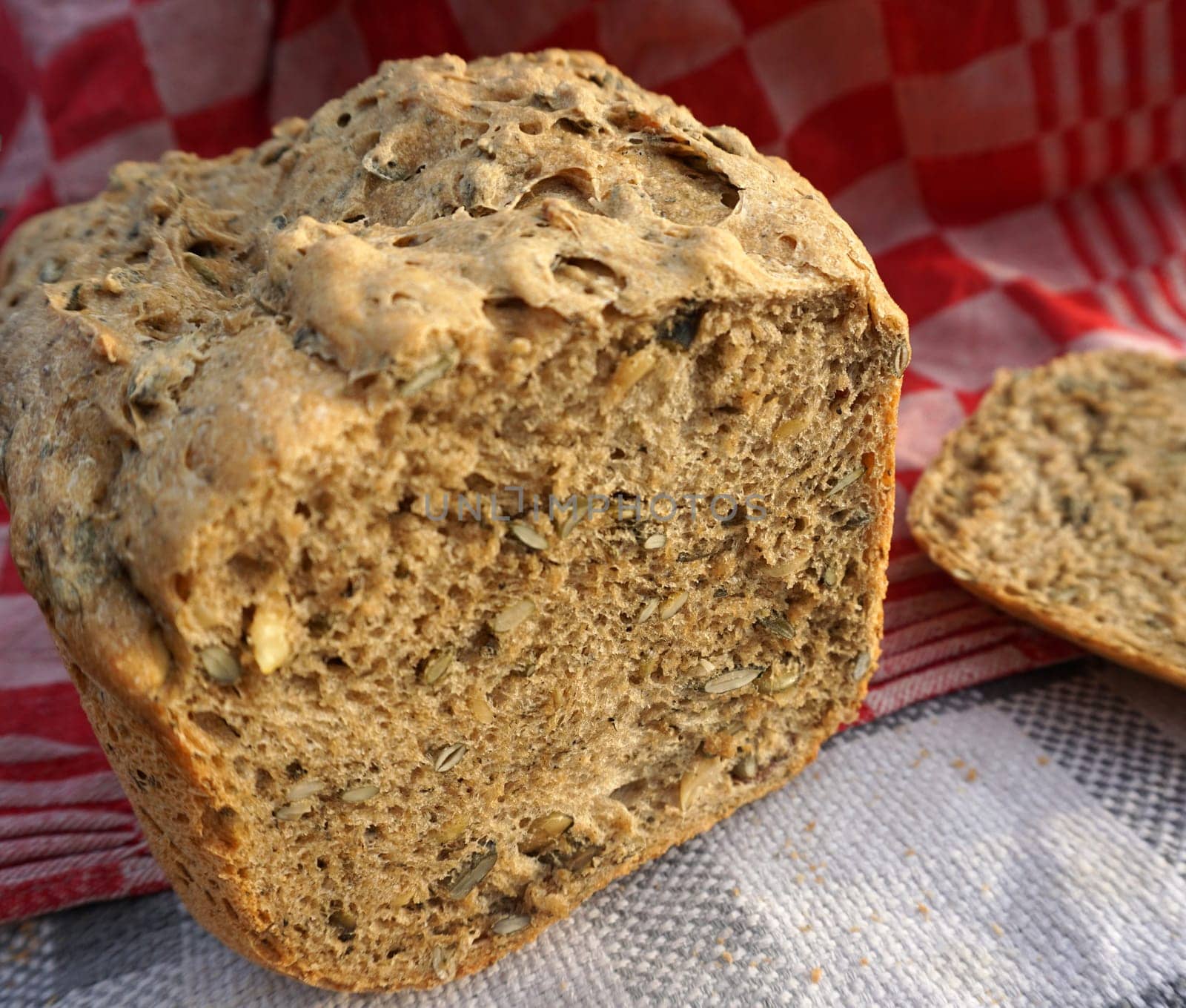 Fresh home made whole grain bread with pumpkin seeds on a red kitchen towel