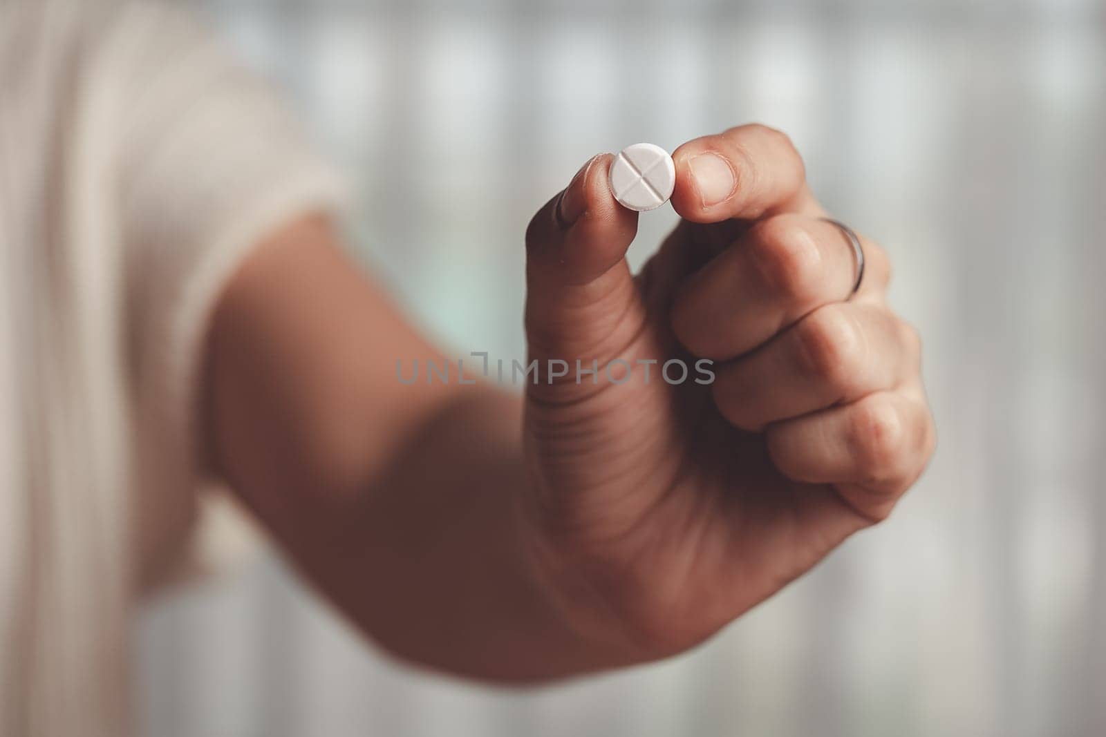 Asian woman's hand holding a white pill for medical and healthcare concept.