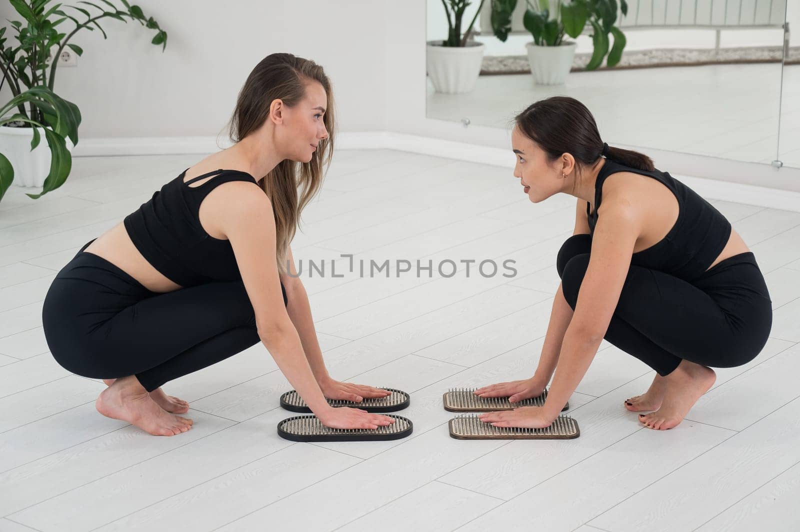 Caucasian and Asian women keep their hands on sadhu boards. Nailing practice