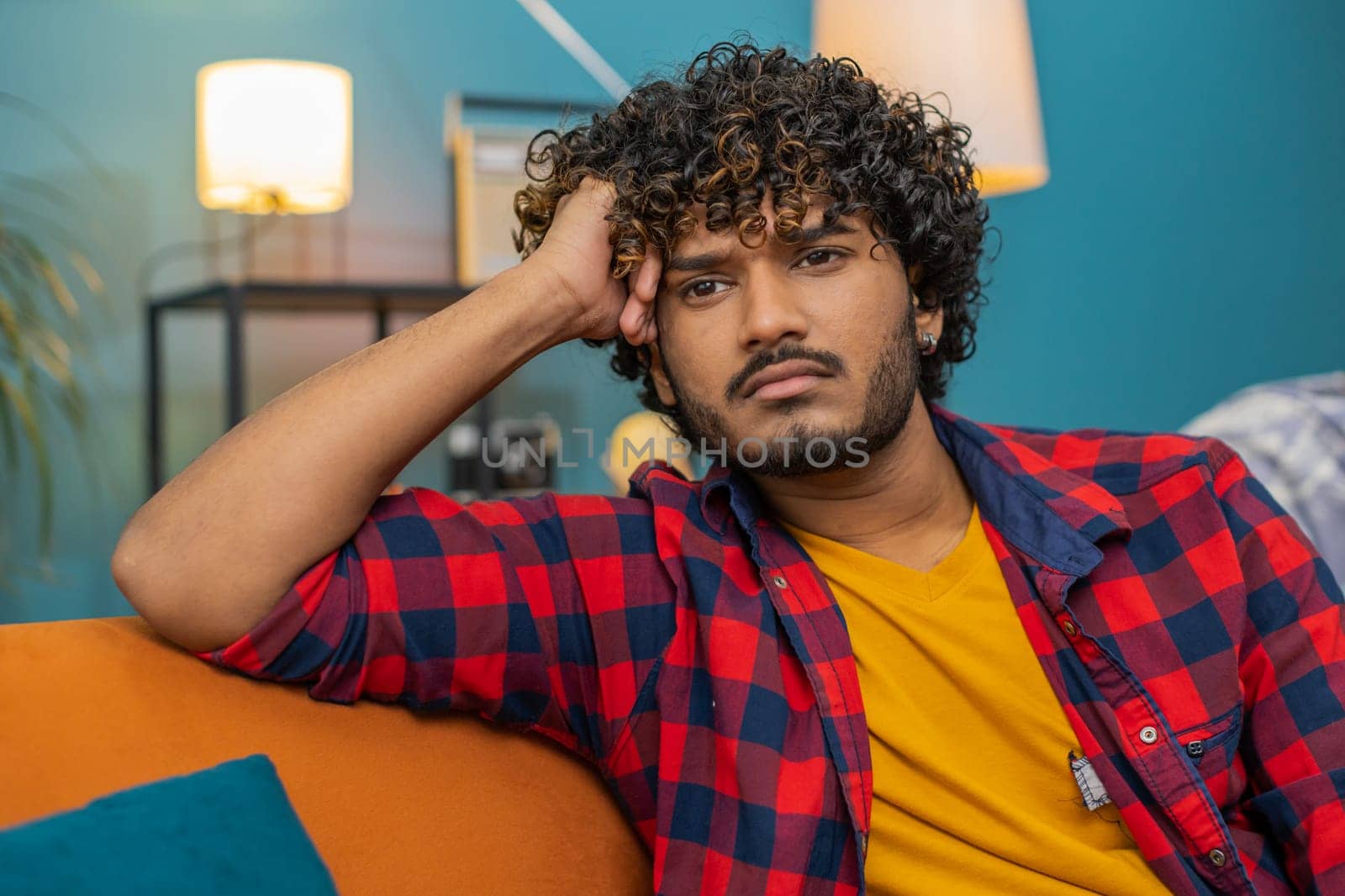 Sad lonely man sitting at home room looks pensive thinks over life concerns or unrequited love suffers from unfair situation. Hindu alone guy problem, break up, depressed feeling bad annoyed burnout