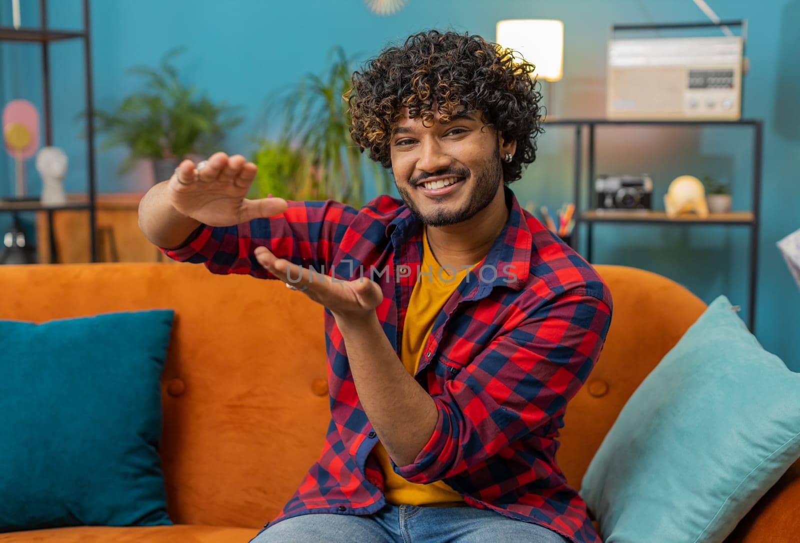Cheerful happy rich indian man showing wasting, throwing money around hand gesture, more tips earnings, big profit, win lottery, body language, share, celebrate. Guy at home in living room apartment