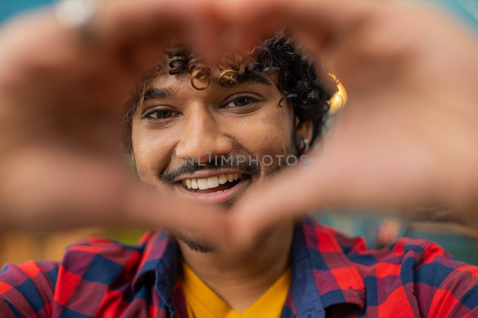 I love you. Happy indian man at home living room couch makes symbol of love, showing heart sign to camera, express romantic feelings express sincere positive feelings. Charity, gratitude, donation