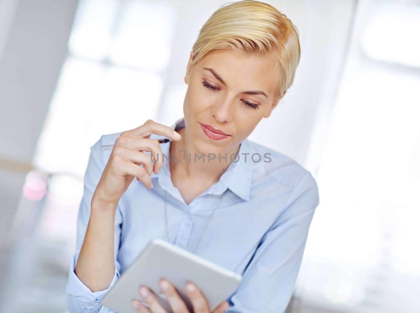 Getting to work on the new project. a young businsswoman using a digital tablet at her desk in the office. by YuriArcurs