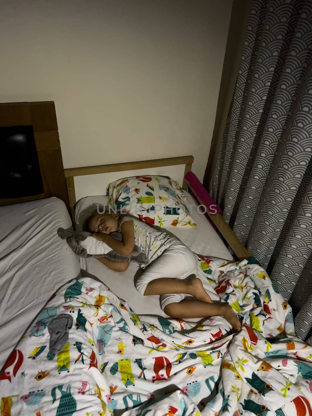 Little girl sleeping on a baby bed hugging a plush toy. High quality photo