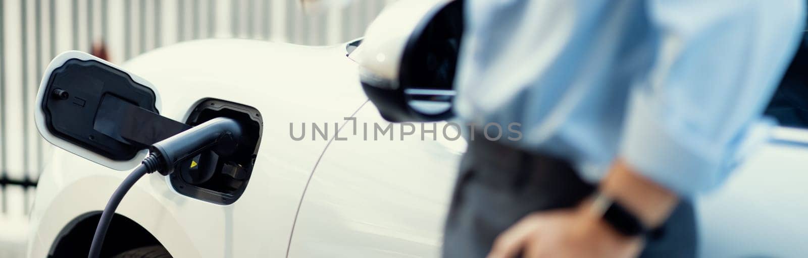 Focus closeup EV car recharge battery at public charging station. by biancoblue