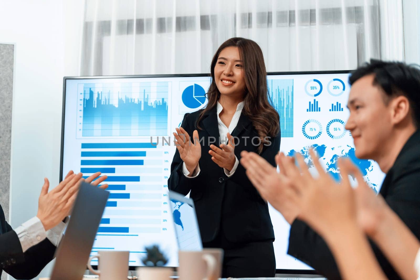 Confidence and young asian businesswoman give presentation on financial business strategy in dashboard report display on screen to colleagues in conference room meeting as harmony in workplace concept