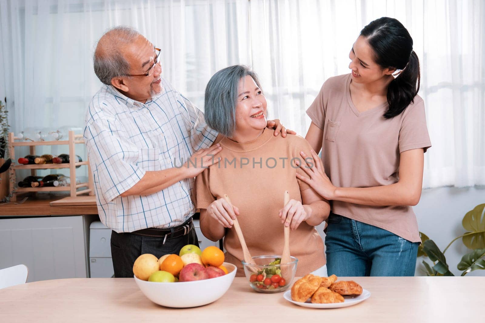 Contented family, daughter, father, mother prepare bread veggies and fruit salad together in their kitchen.