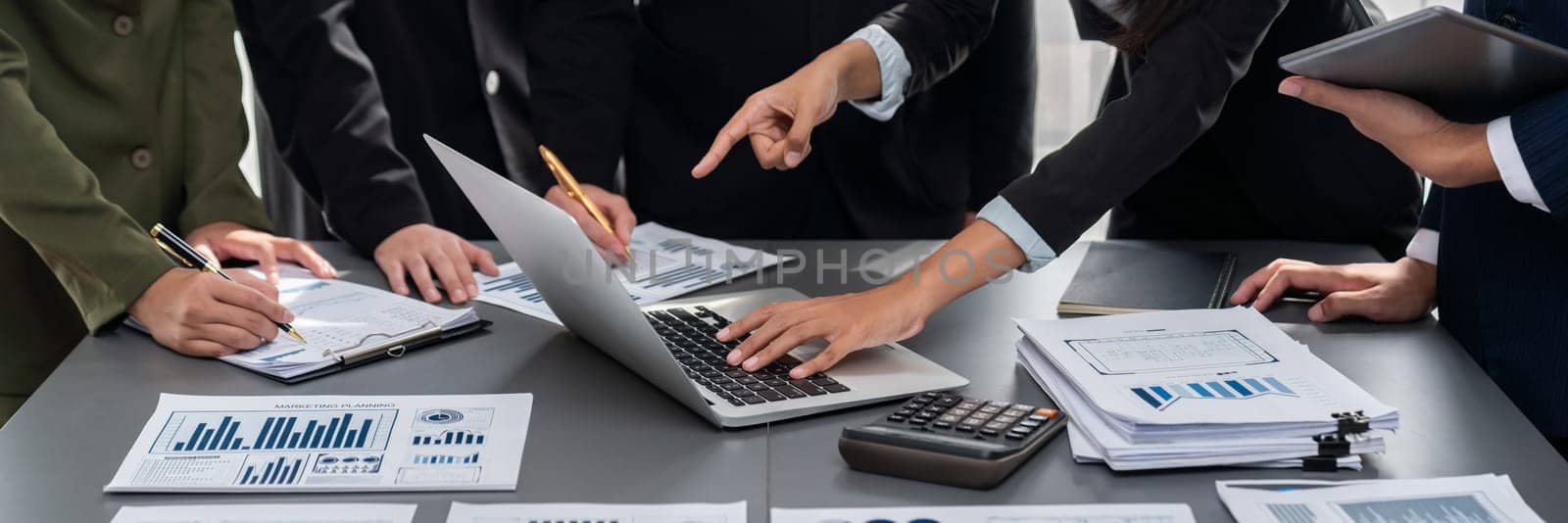 Analyst team working on BI Fintech to analyze financial dashboard paper at office workplace. Businesspeople reviewing report paper on table for business insight. Panorama shot. Prodigy