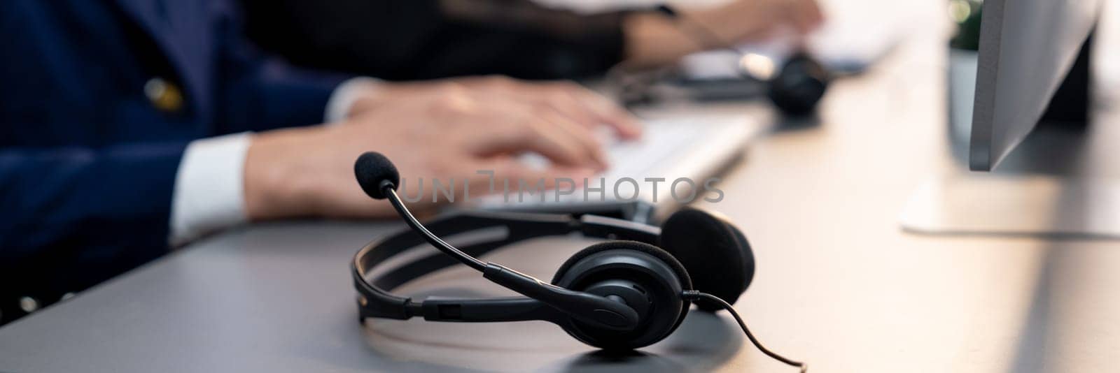 Panorama focus headset on call center workspace desk with blur background of operator team or telesales representative engage in providing client with customer support service or making sales. Prodigy