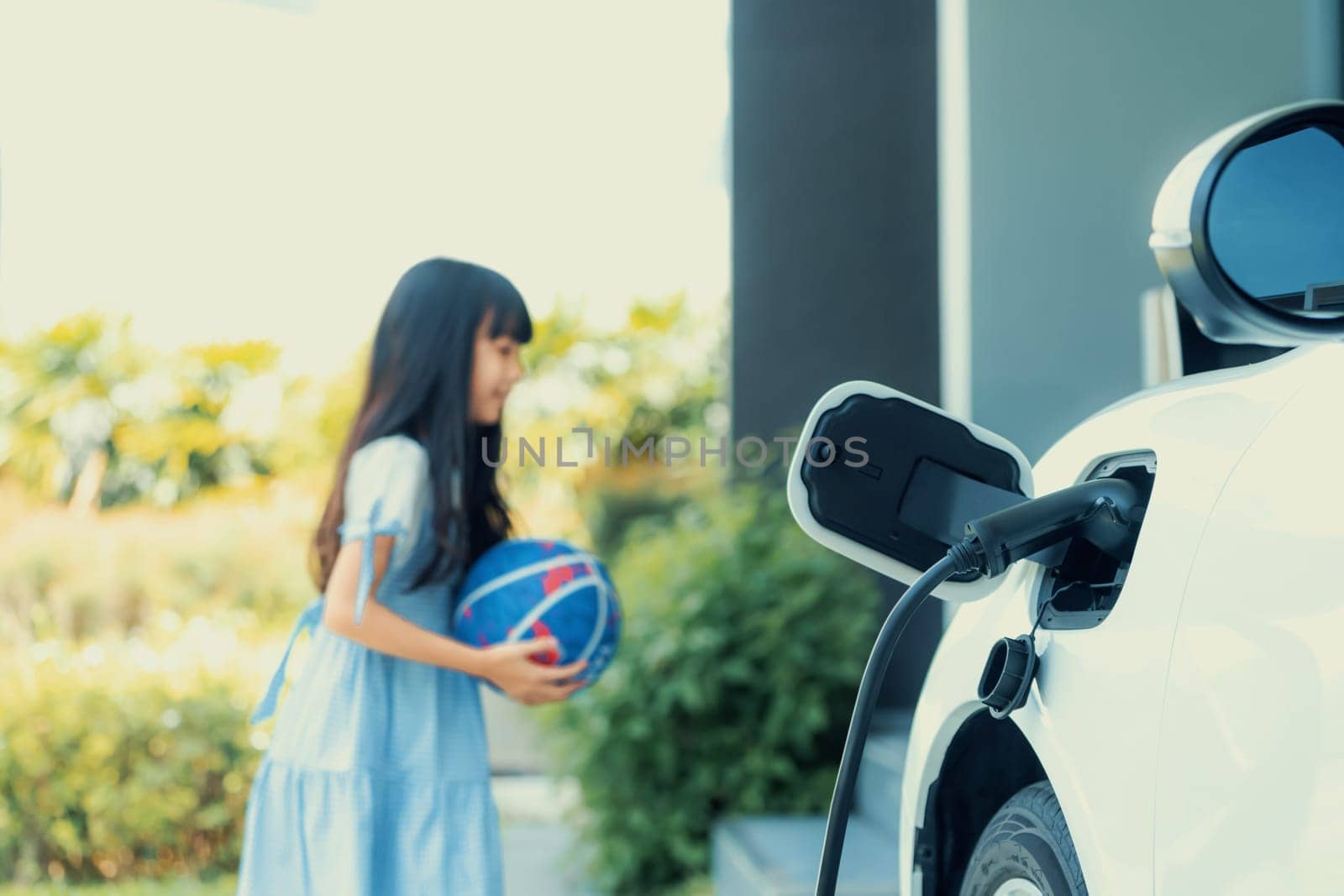 Progressive technology concept of focus EV charger with blur young girl backdrop by biancoblue