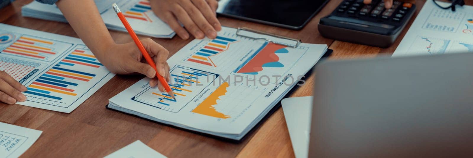 Analyst team utilizing BI Fintech to analyze and pointing at financial dashboard paper office. Businesspeople examining report paper on table for business insight. Panorama shot. Scrutinize