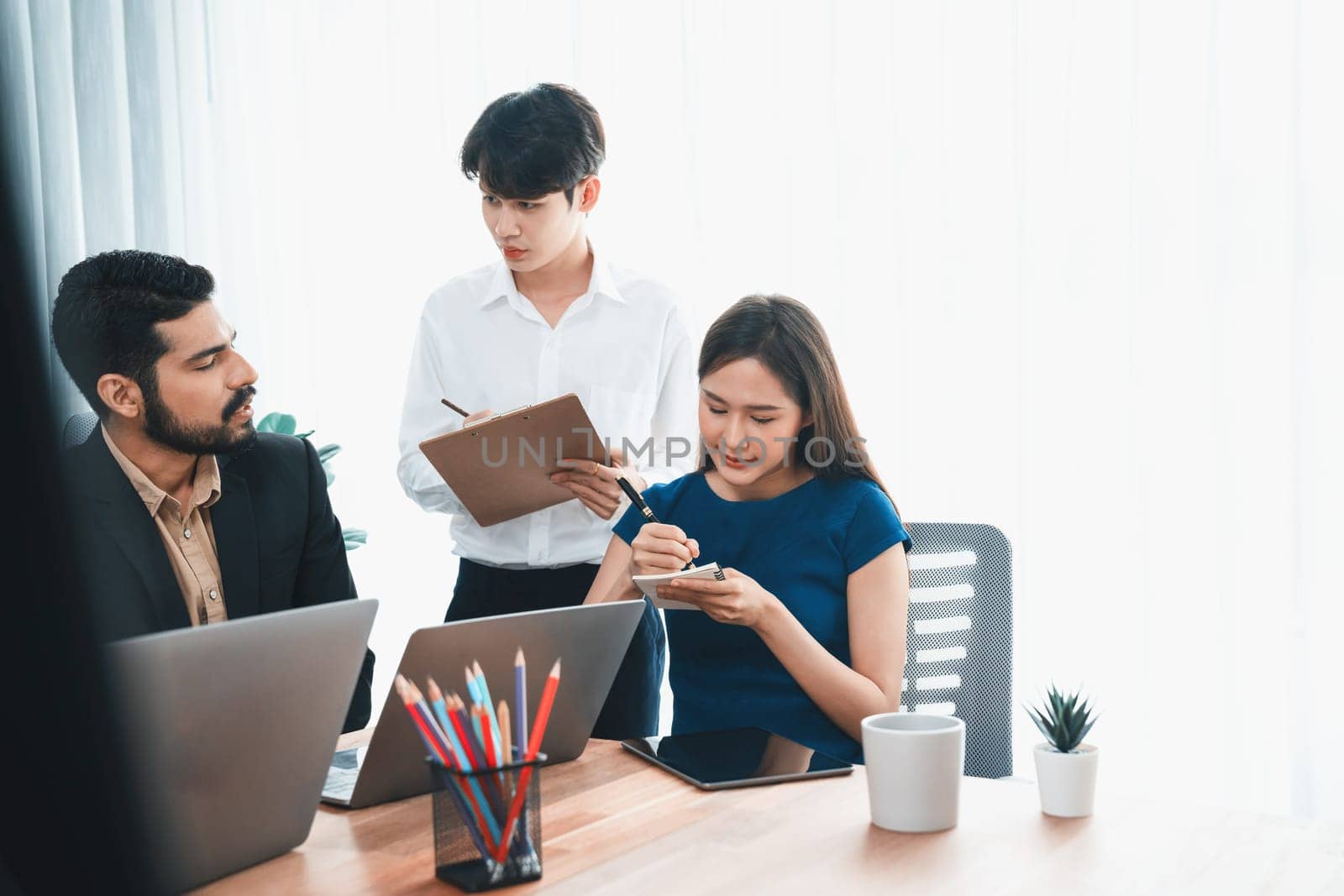 Professional Asian employee work together as team in corporate office, discussing business plans and data to achieve success on desk with laptop. Modern office worker teamwork concept. Concord