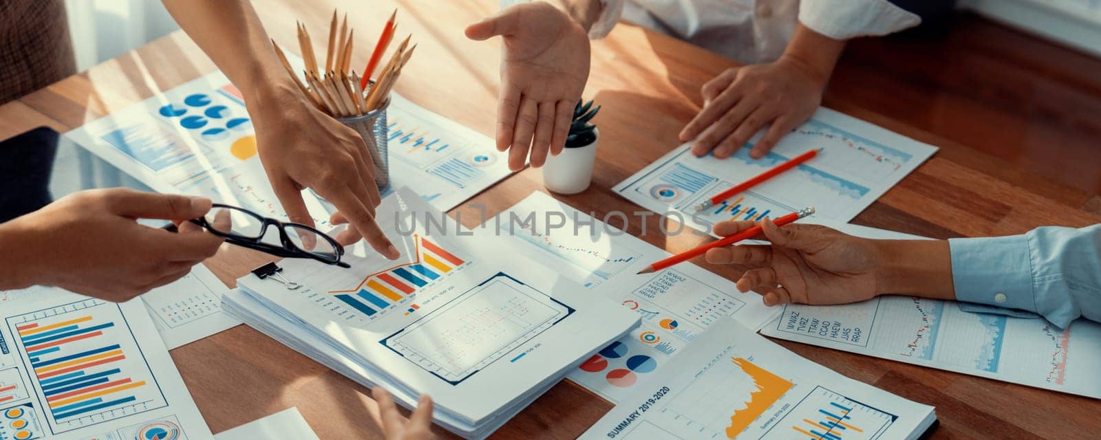 Analyst team utilizing BI Fintech to analyze and pointing at financial dashboard paper office. Businesspeople examining report paper on table for business insight. Panorama shot. Scrutinize