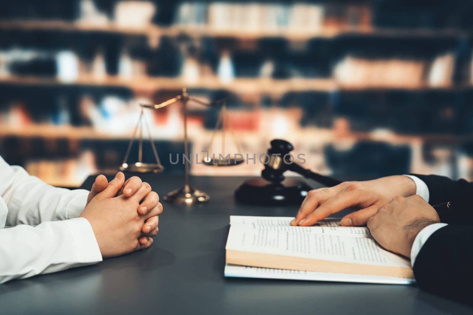 Closeup lawyer colleagues preparing for lawsuit or litigation, reading and pointing hand on legal book on desk at library for educational law school concept, decorated with legal symbols. Equilibrium