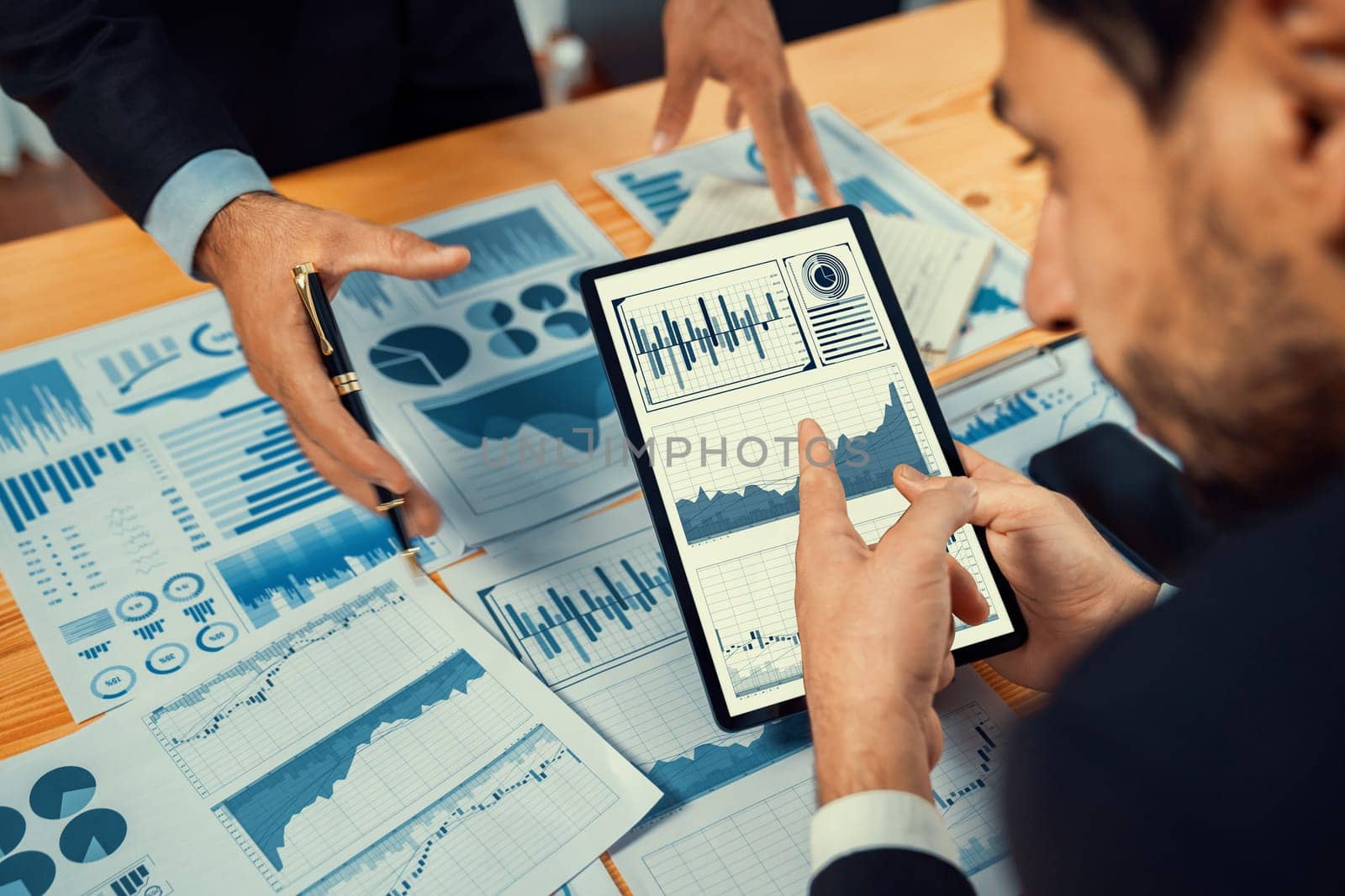 Busy analyst team discussing financial data on digital dashboard, analyzing chart and graph using data science software display on a tablet screen. Business intelligence and Fintech. Fervent