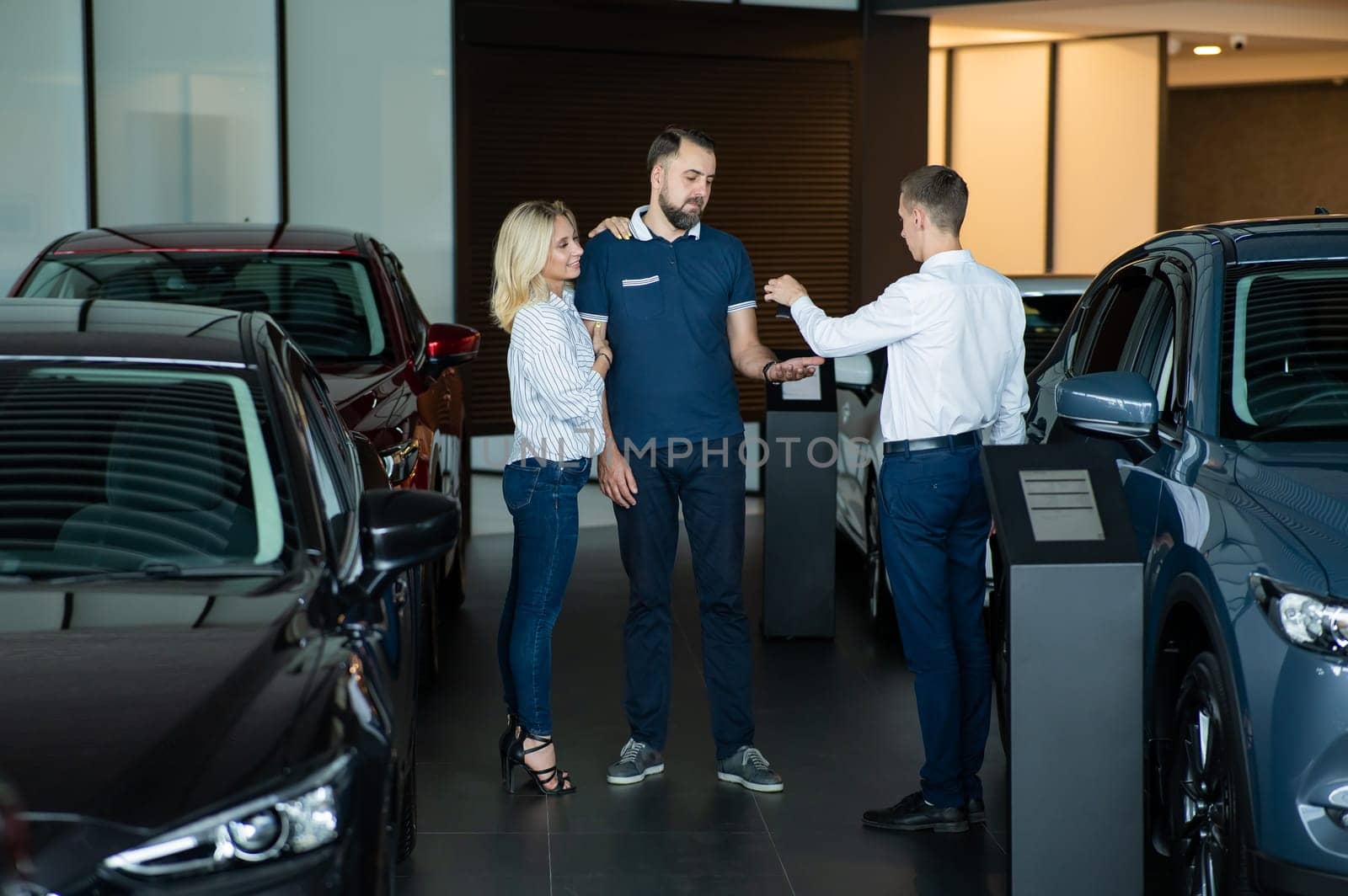 The seller hands over the car keys to the buyers. The couple bought a new car