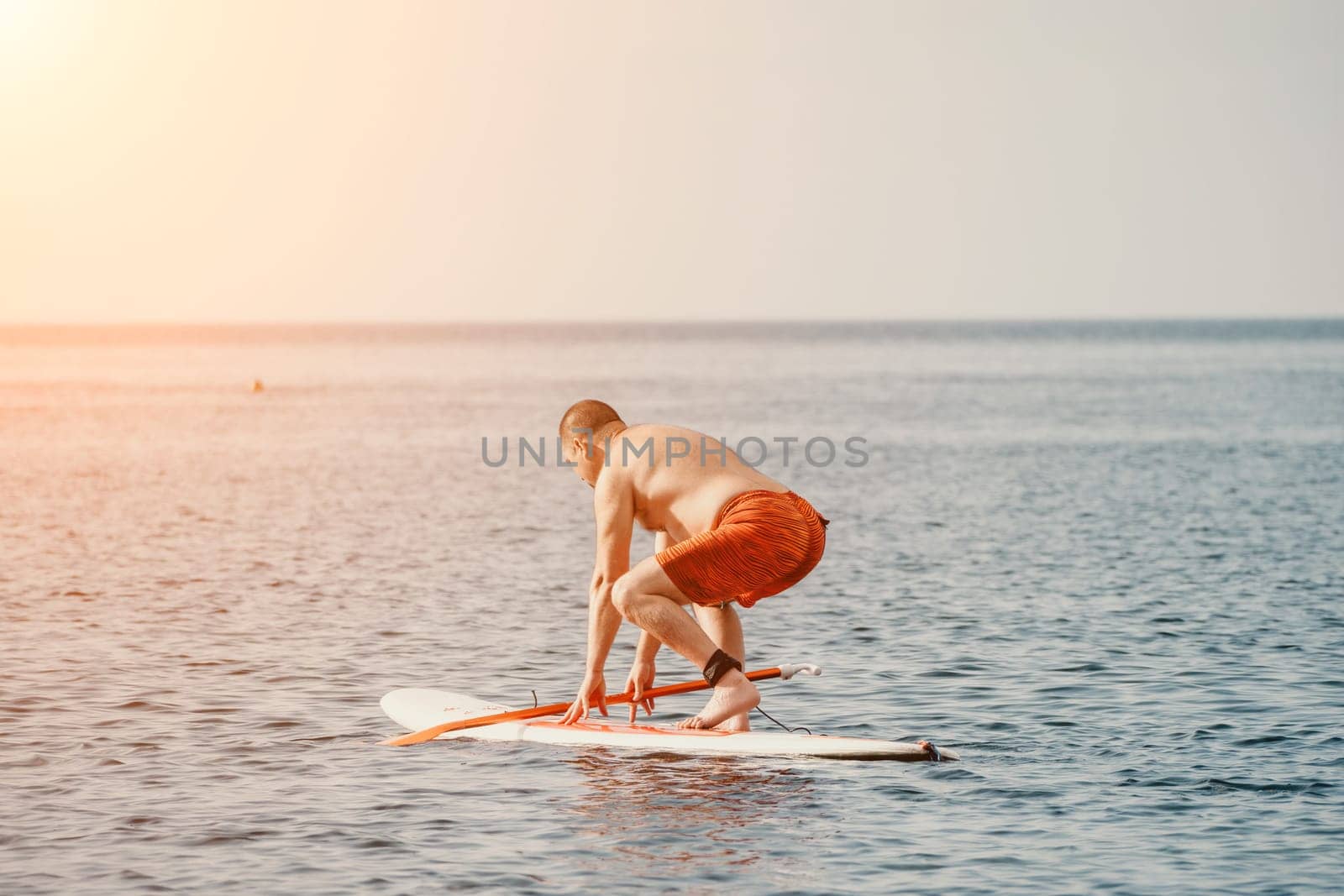 Active mature male paddler with his paddleboard and paddle on a sea at summer. Happy senior man stands with a SUP board. Stand up paddle boarding - outdor active recreation in nature. by panophotograph
