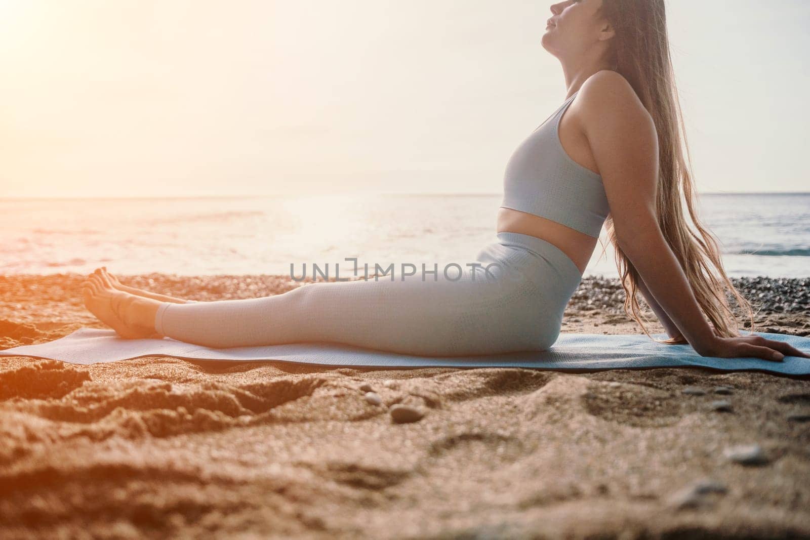 Middle aged well looking woman with black hair doing Pilates with the ring on the yoga mat near the sea on the pebble beach. Female fitness yoga concept. Healthy lifestyle, harmony and meditation.