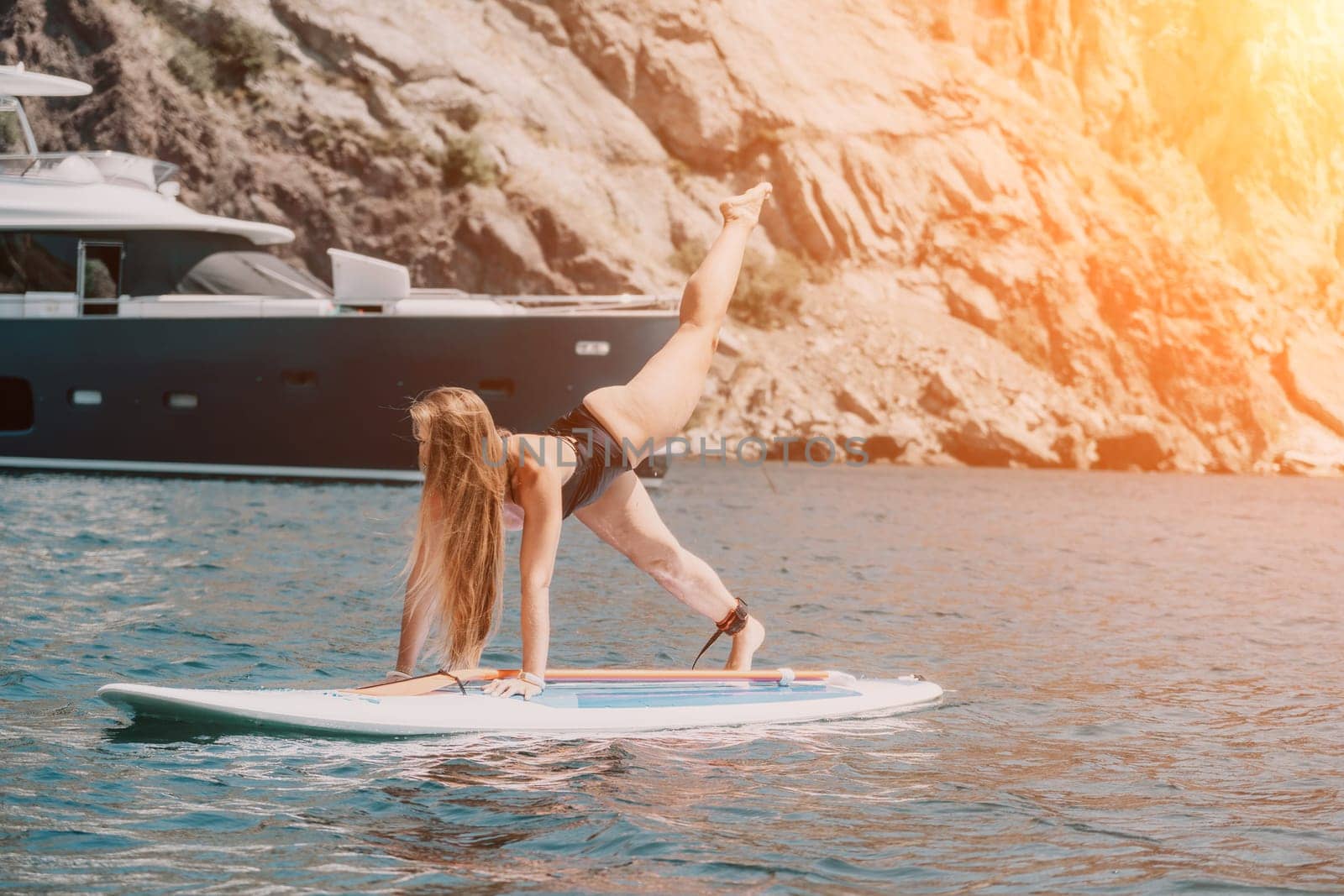 Close up shot of beautiful young caucasian woman with black hair and freckles looking at camera and smiling. Cute woman portrait in a pink bikini posing on a volcanic rock high above the sea