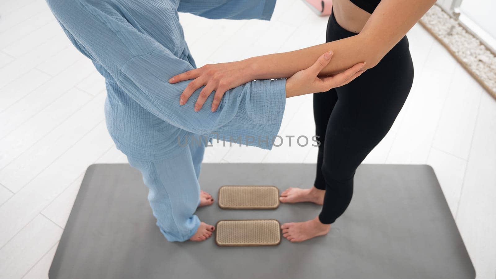 Caucasian woman stands on sadhu boards with therapist support