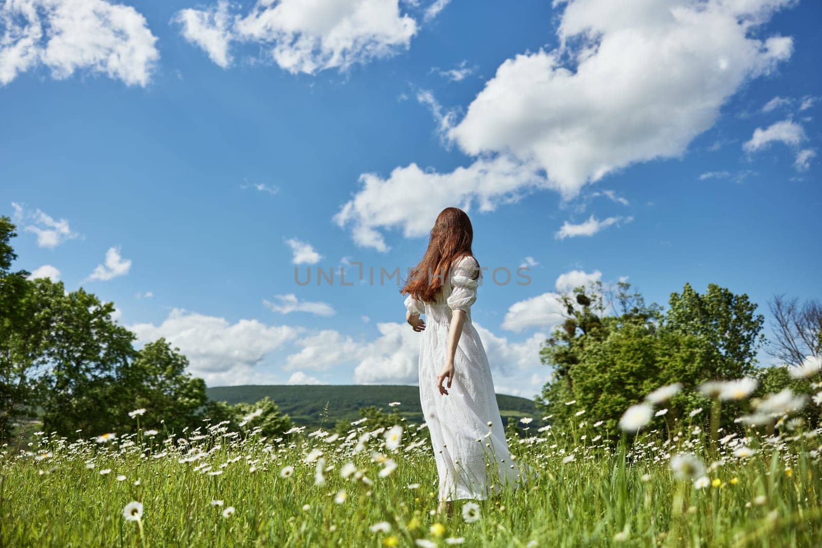 a woman in a long light dress stands in a chamomile field and holds out her hand to a clear, clear sky by Vichizh
