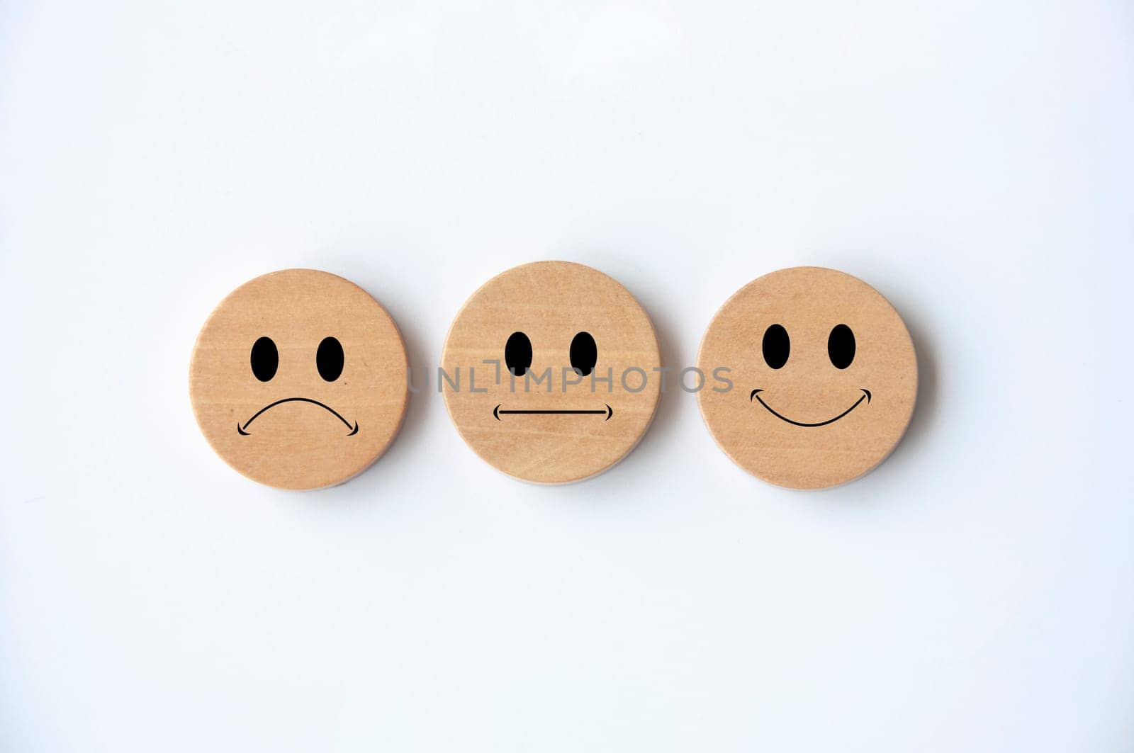 Happy, sad and neutral emoticon faces on wooden circle with white background cover. Customer feedback, satisfaction and evaluation and concept.