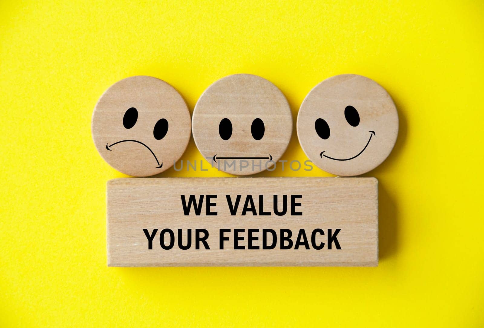 We value your feedback text on wooden block with happy, sad and neutral emoticon faces on wooden circle. Customer feedback, satisfaction and evaluation and concept.