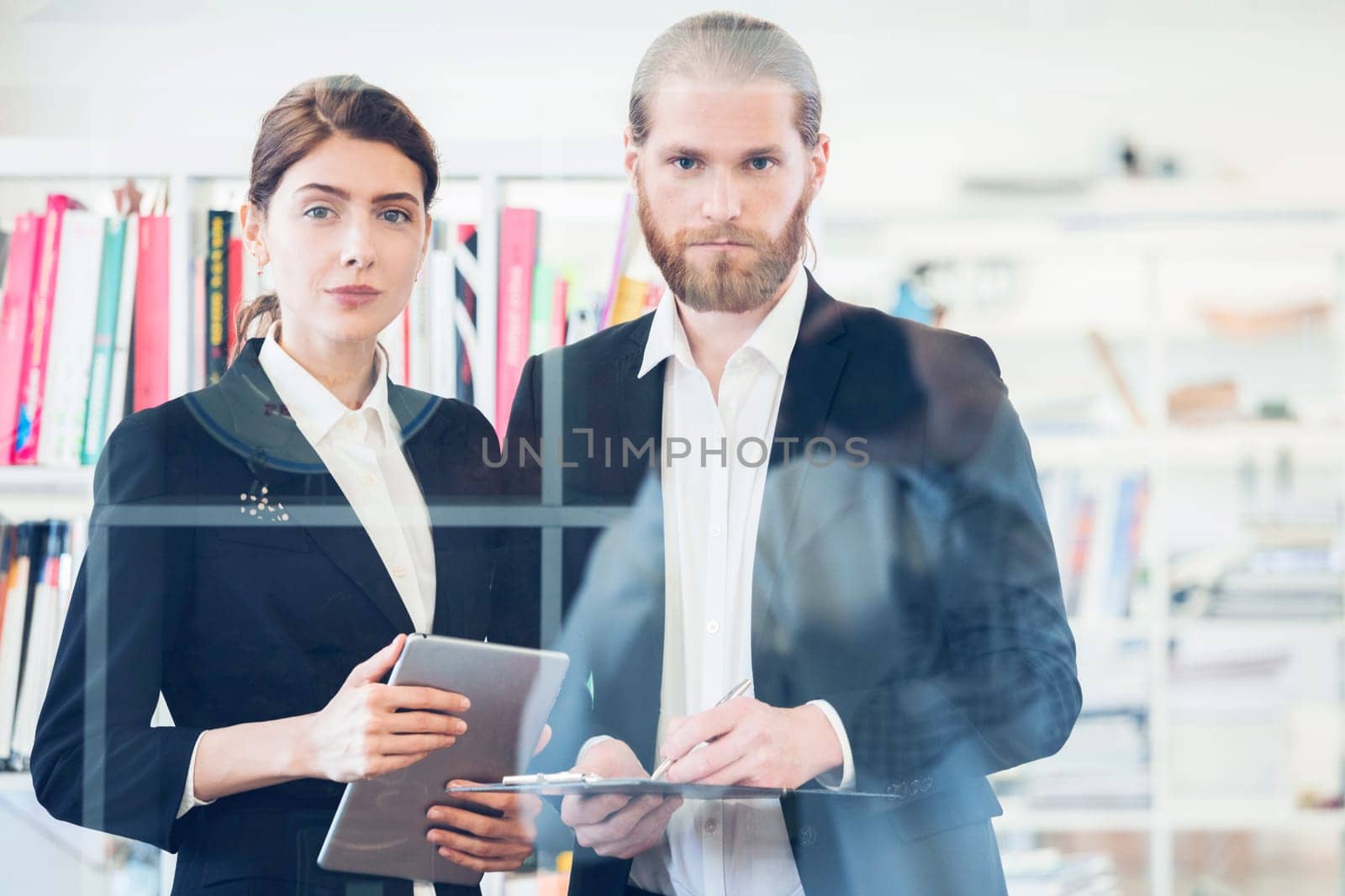 Portrait of business people with documents in office through the glass