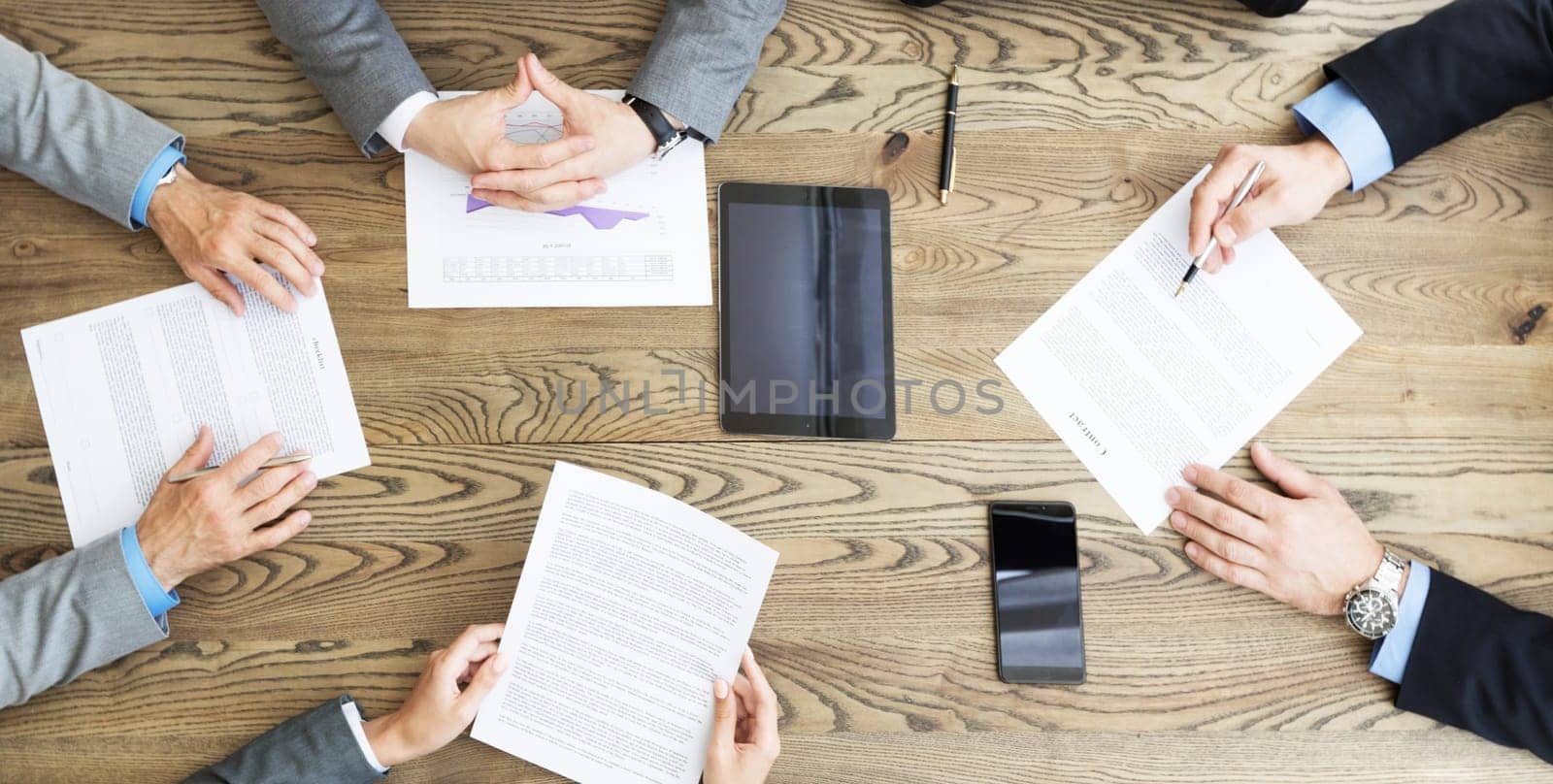 Top view of confident business men in suits sitting at wooden table and discussing new contract terms before signing it top view