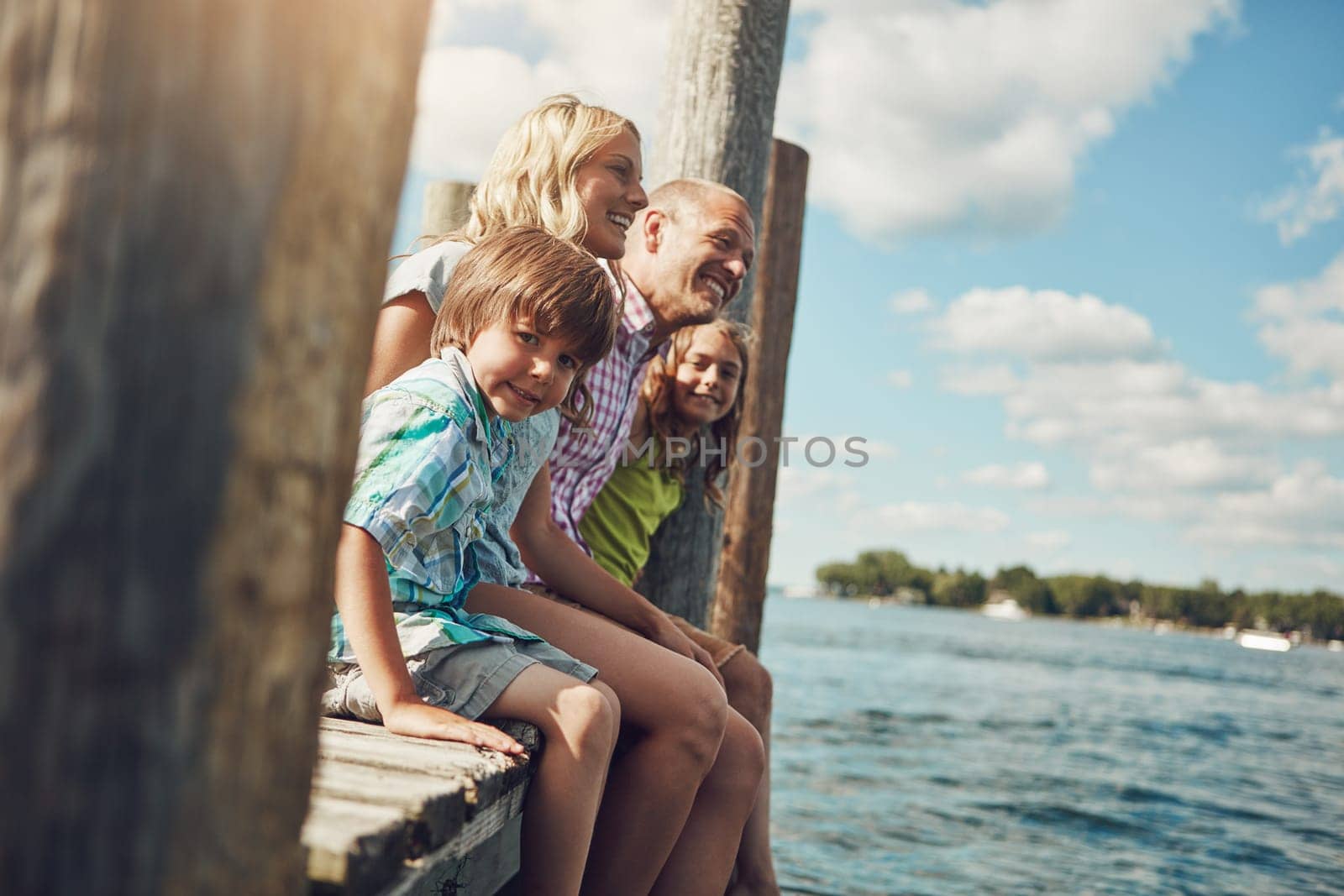 Family means the world to us. a young family on a pier while out by the lake. by YuriArcurs