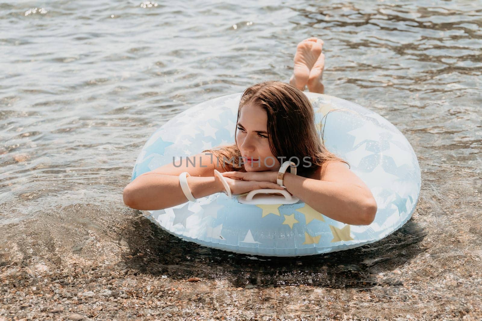 Woman summer sea. Happy woman swimming with inflatable donut on the beach in summer sunny day, surrounded by volcanic mountains. Summer vacation concept