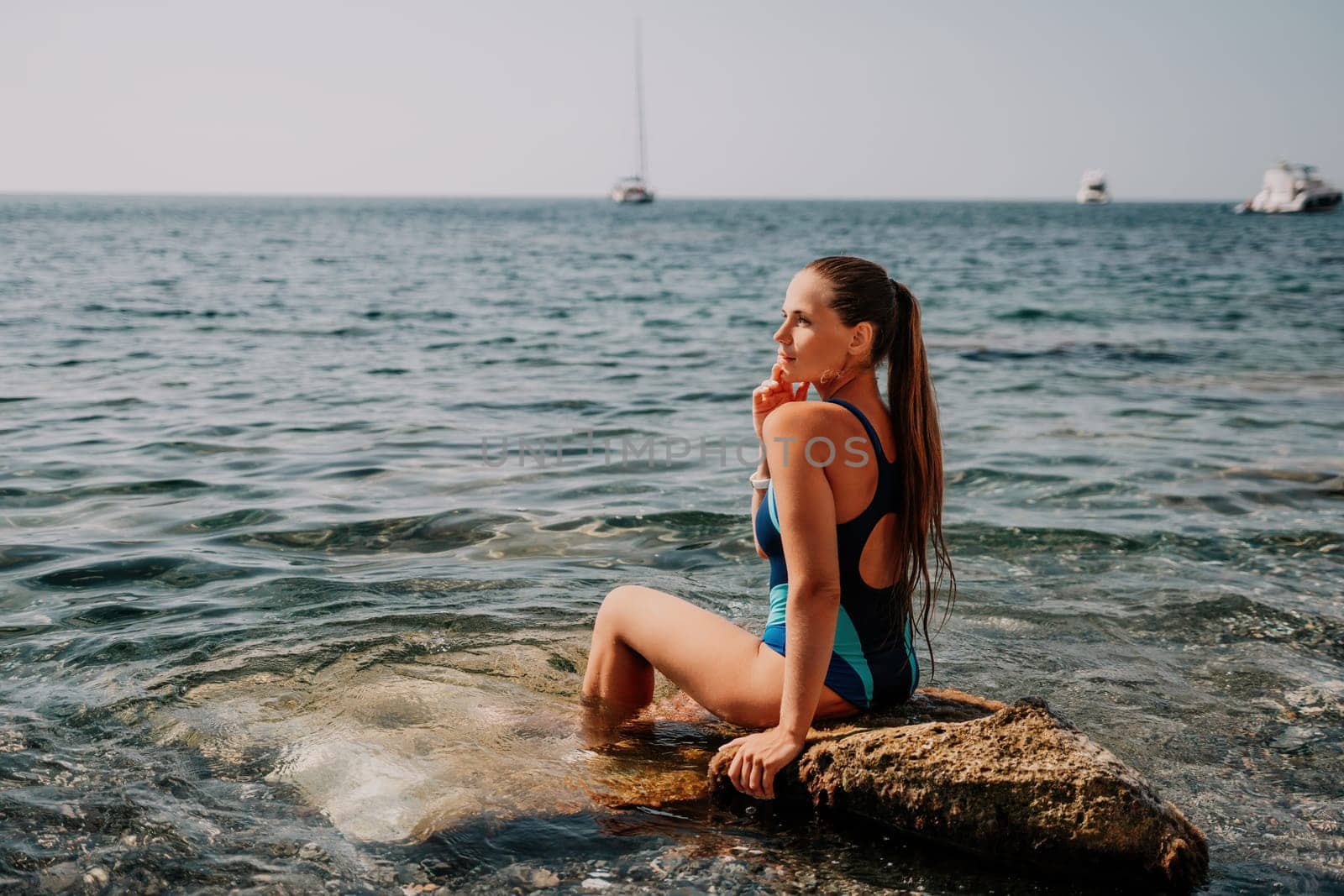 Woman travel sea. Young Happy woman in a long red dress posing on a beach near the sea on background of volcanic rocks, like in Iceland, sharing travel adventure journey