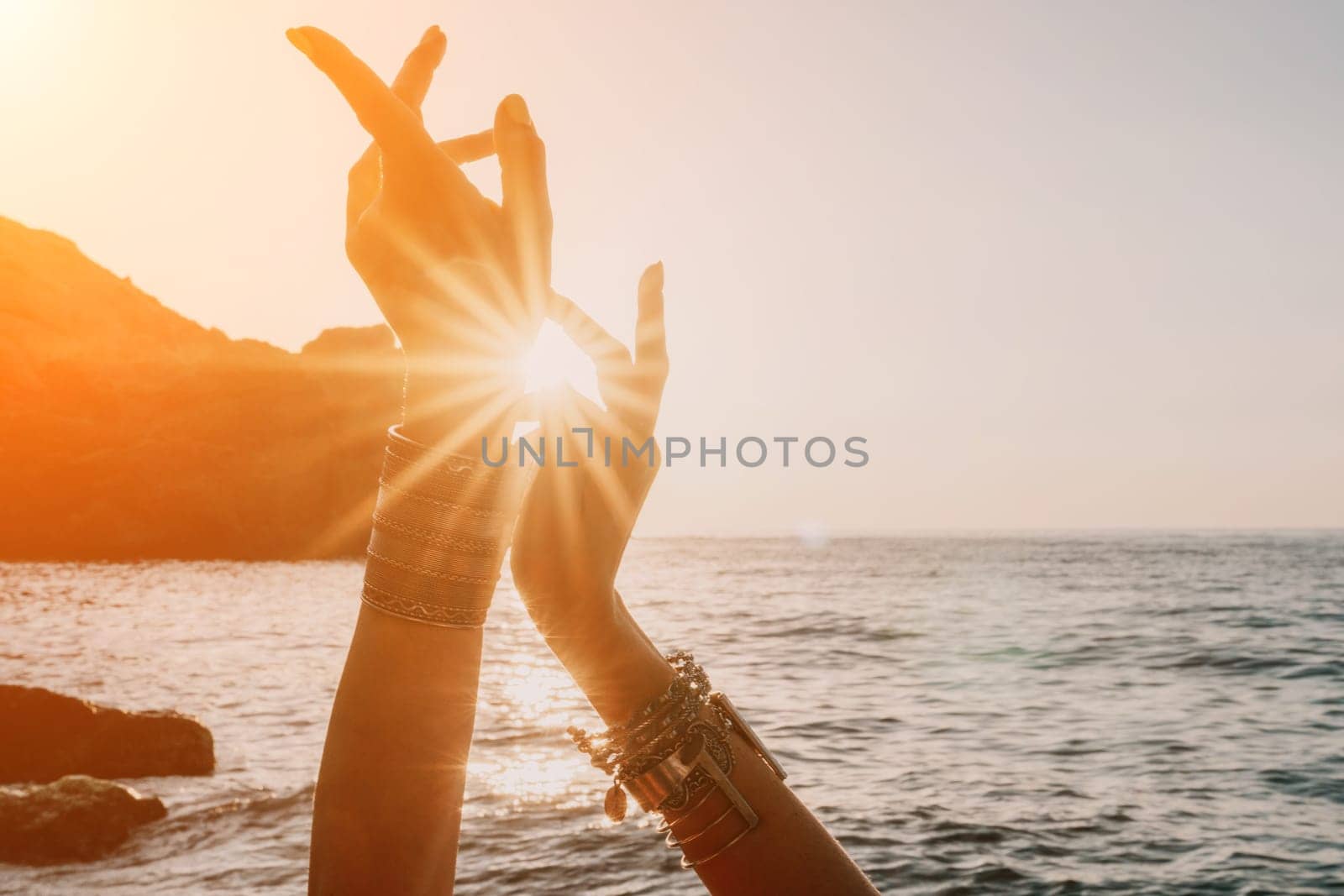 Young woman in swimsuit with long hair practicing stretching outdoors on yoga mat by the sea on a sunny day. Women's yoga fitness pilates routine. Healthy lifestyle, harmony and meditation concept.