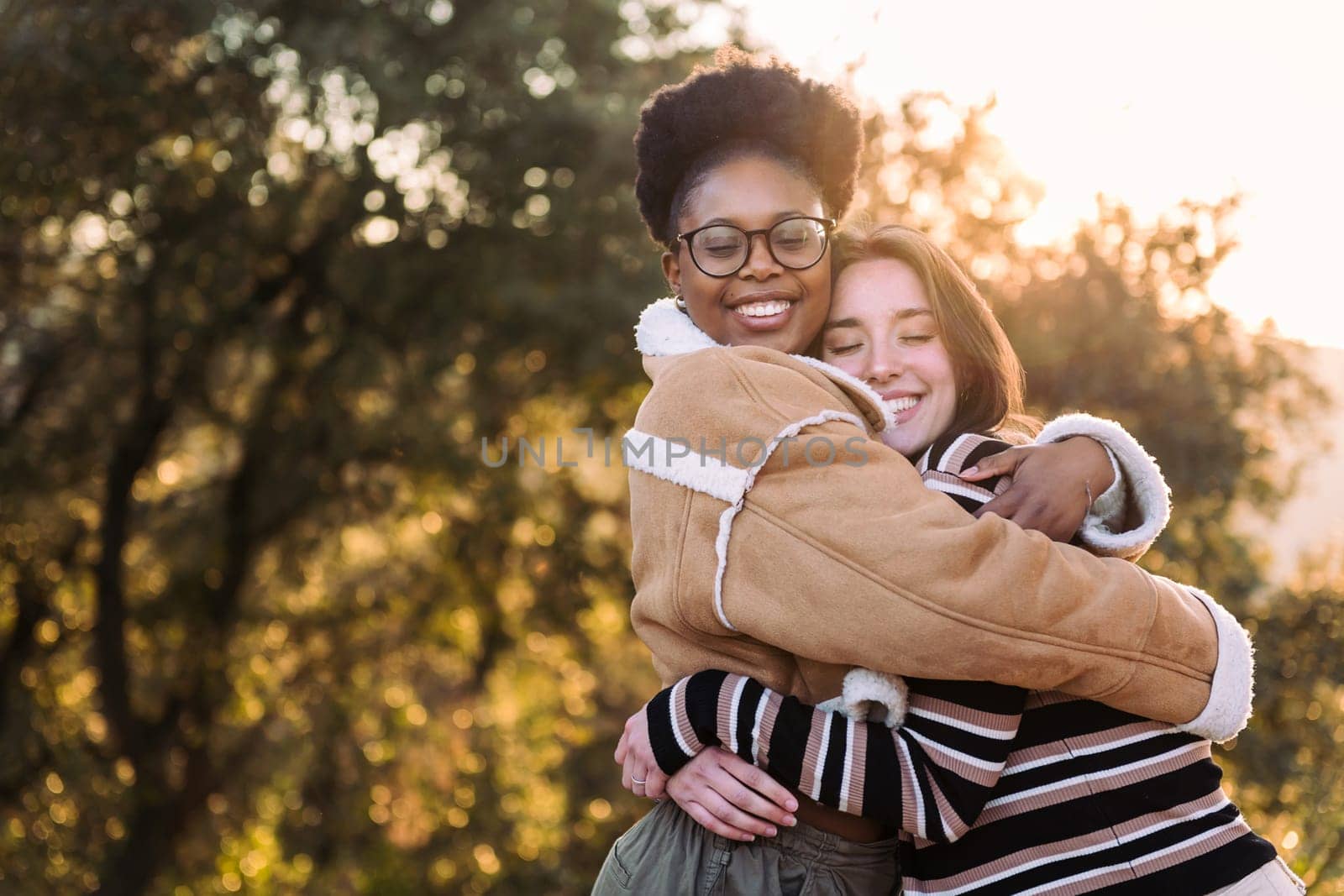 two lovely friends hugging in nature at sunset, concept of active tourism and female friendship, copy space for text