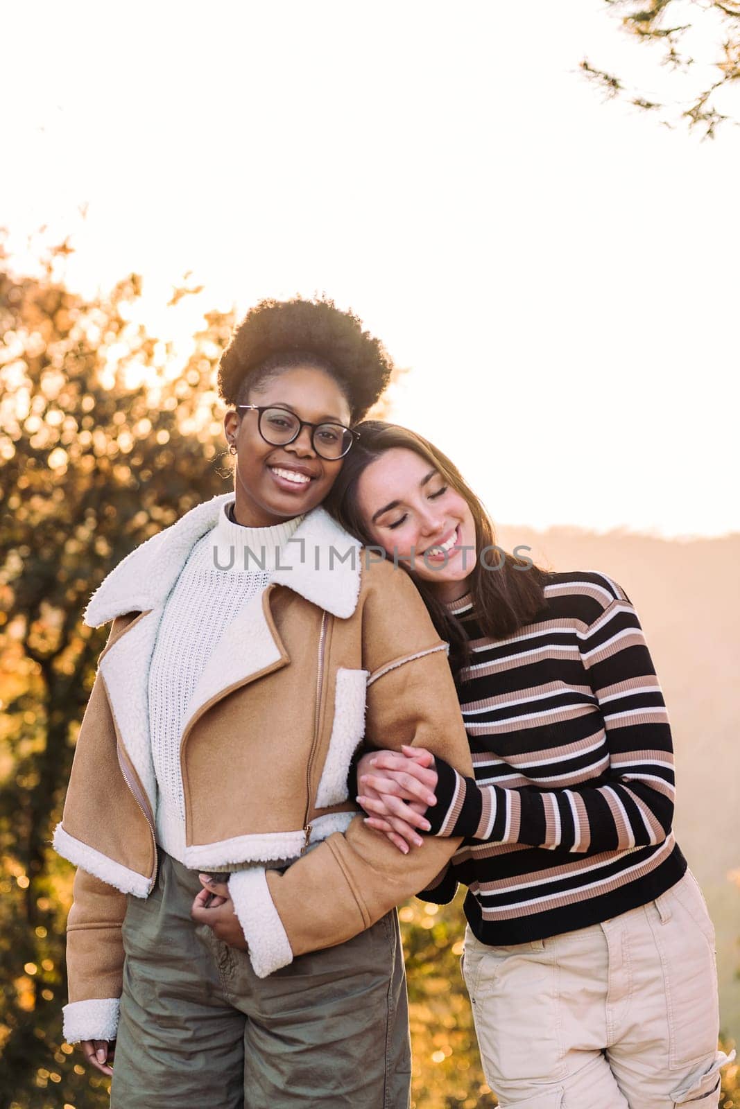 two young friends smiling happy embracing in nature at sunset, concept of active tourism and female friendship, copy space for text