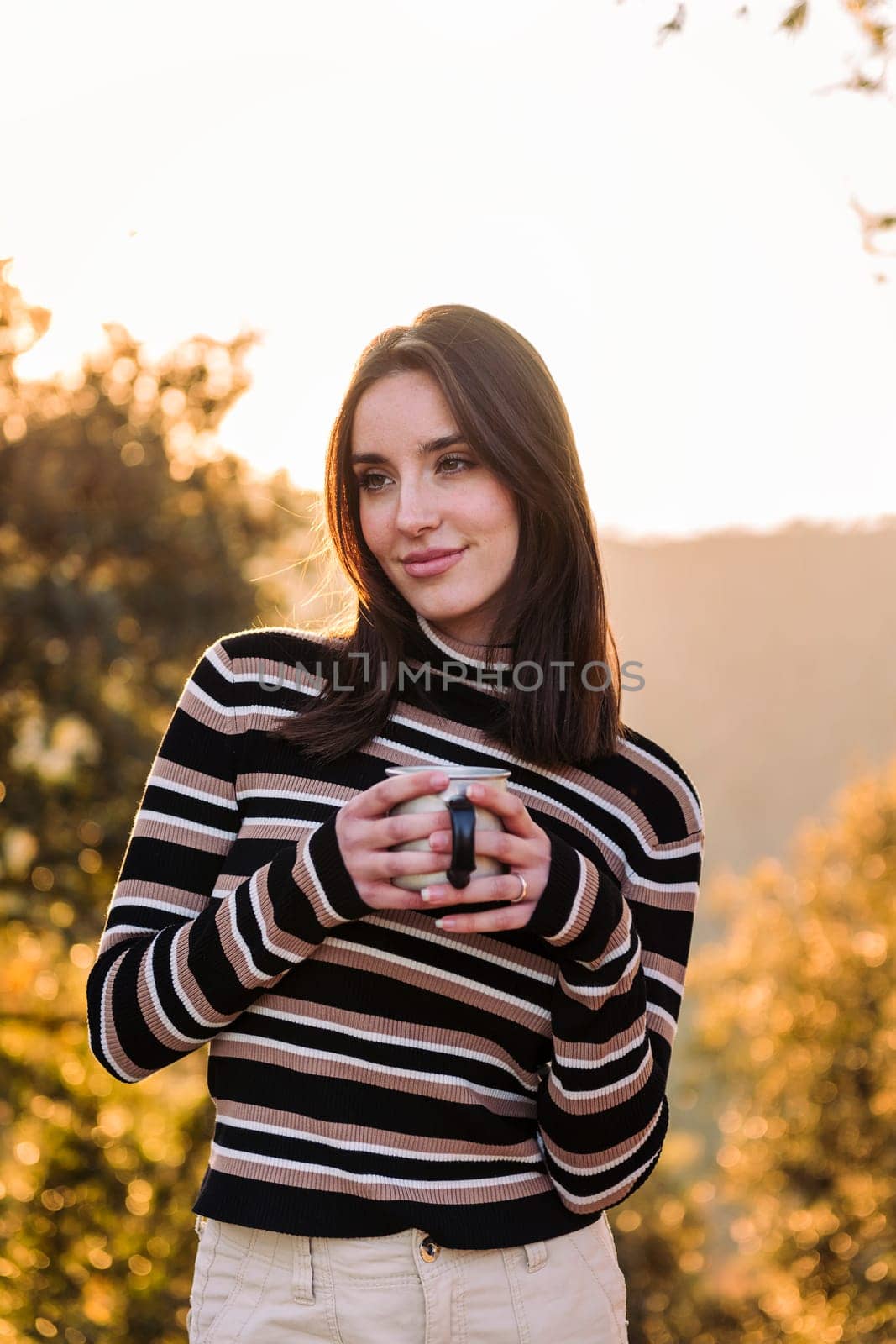 young woman savoring hot drink in nature, concept of morning bliss and wilderness lifestyle, copy space for text